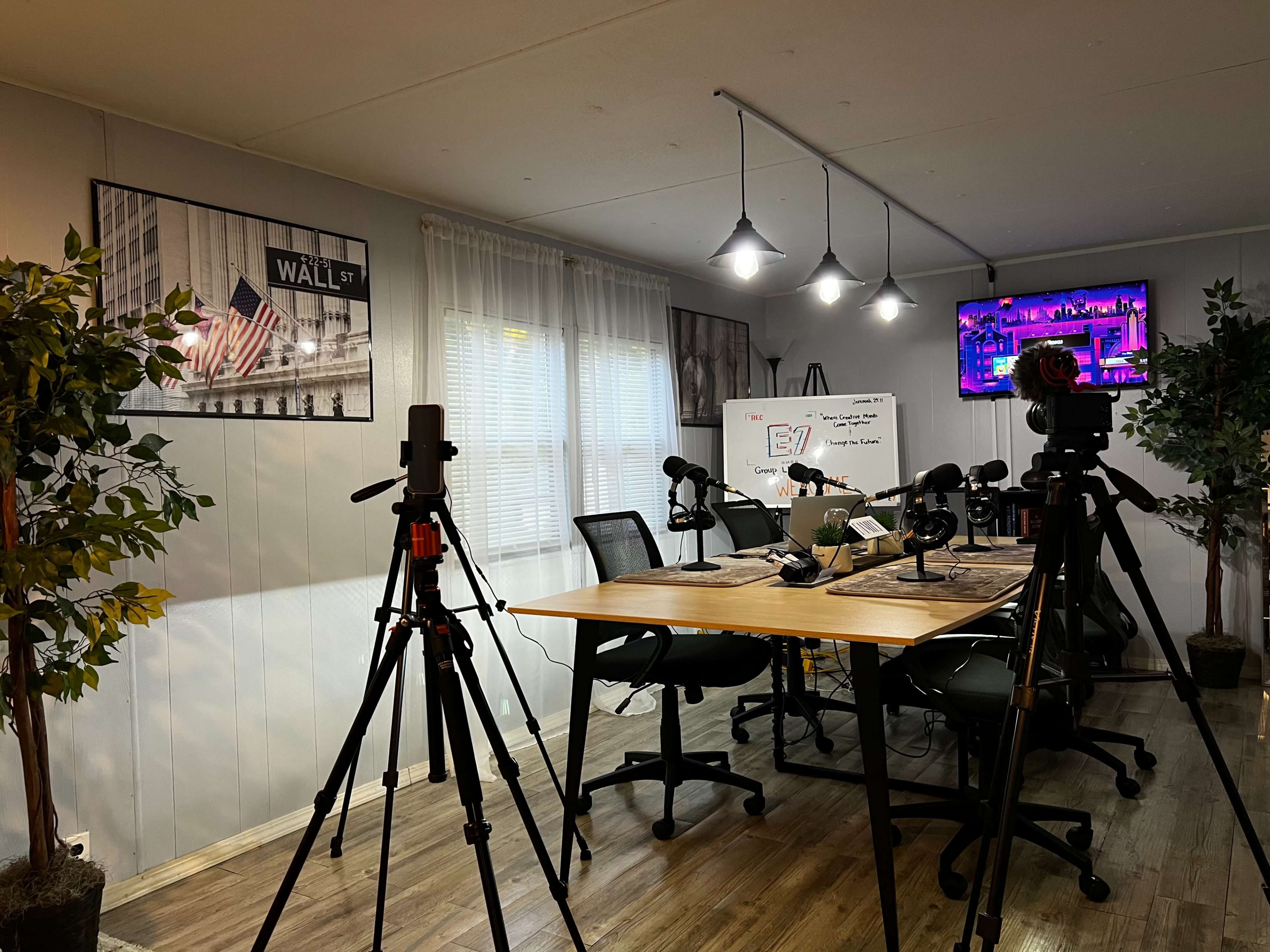 A video recording setup with multiple cameras, microphones, and a table arranged for a discussion in a well-lit room.