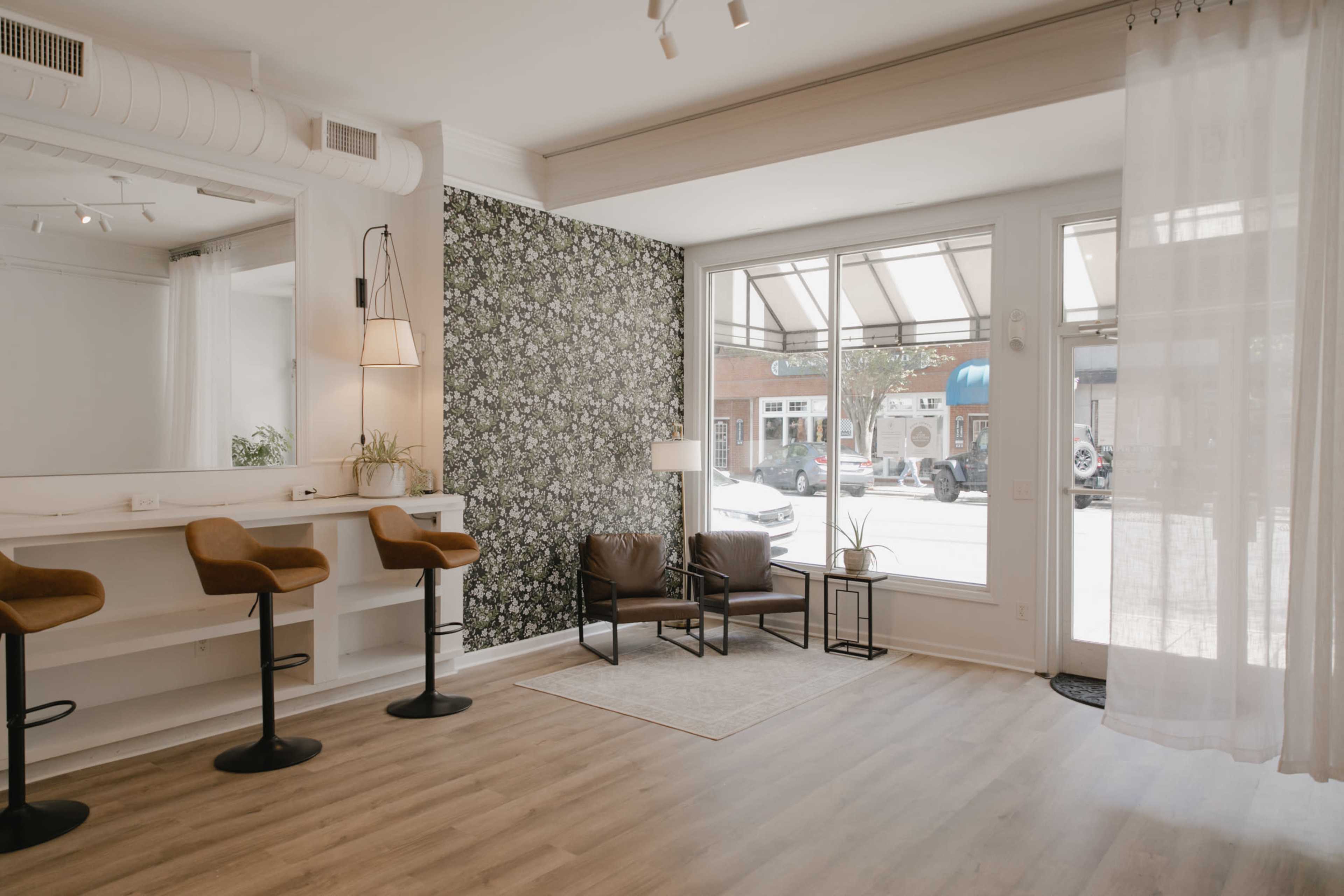 A modern interior of a boutique space with bar seating, a patterned accent wall, and large windows allowing natural light to enter.