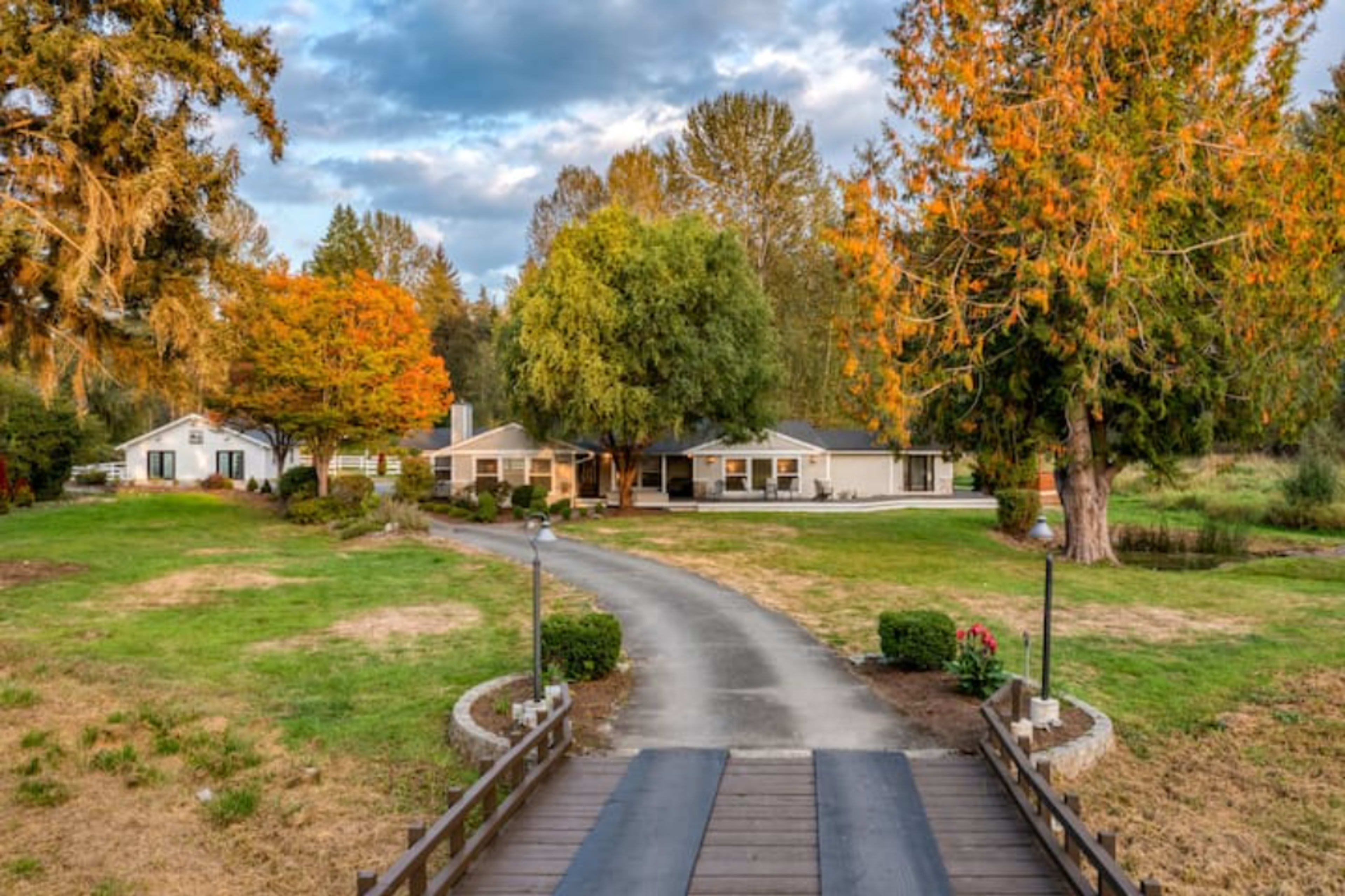 A long driveway leads to a spacious home surrounded by trees and a grassy area.