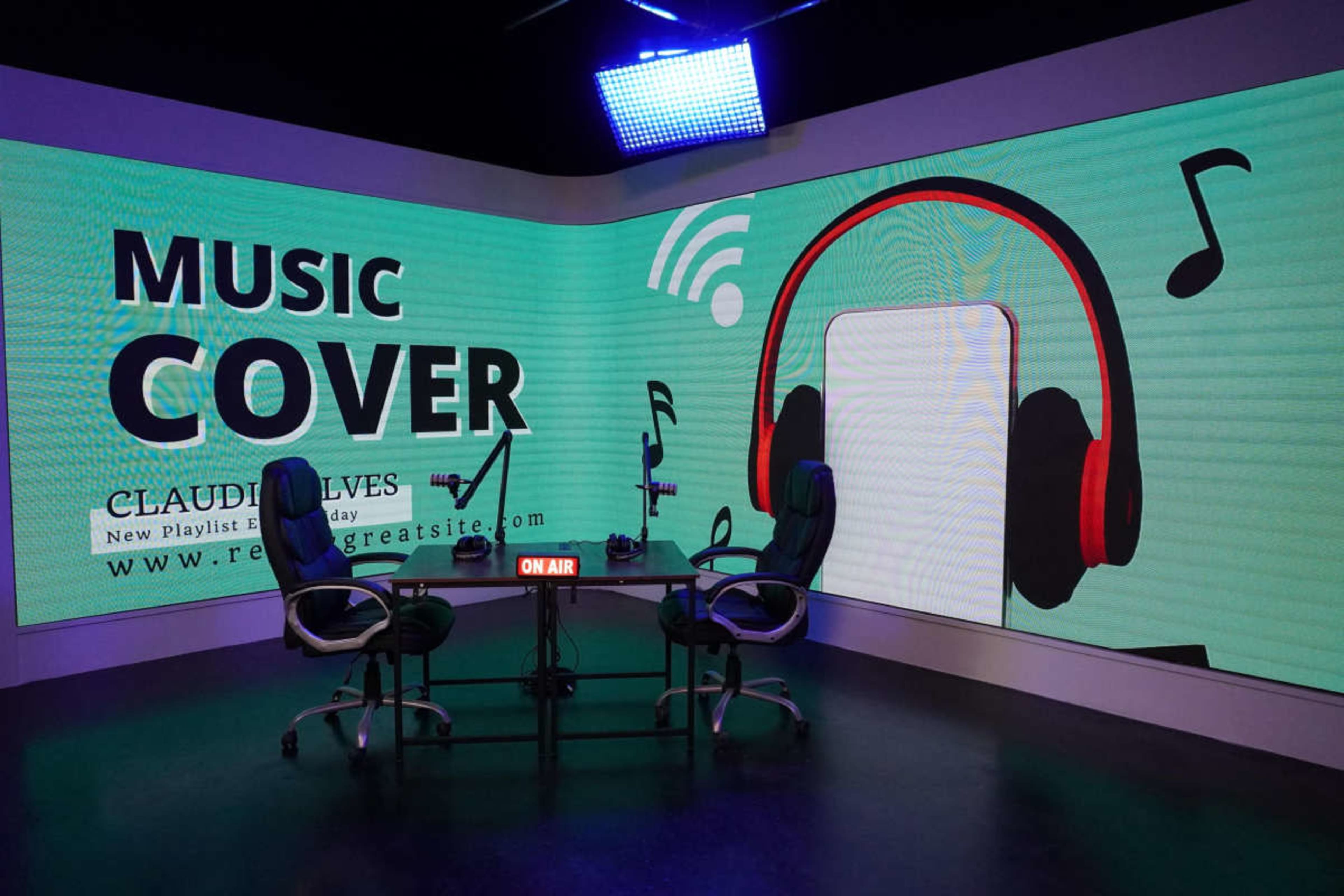 The image shows a modern studio setup with two chairs and a large digital screen displaying the words "MUSIC COVER" alongside graphics of headphones and musical notes.