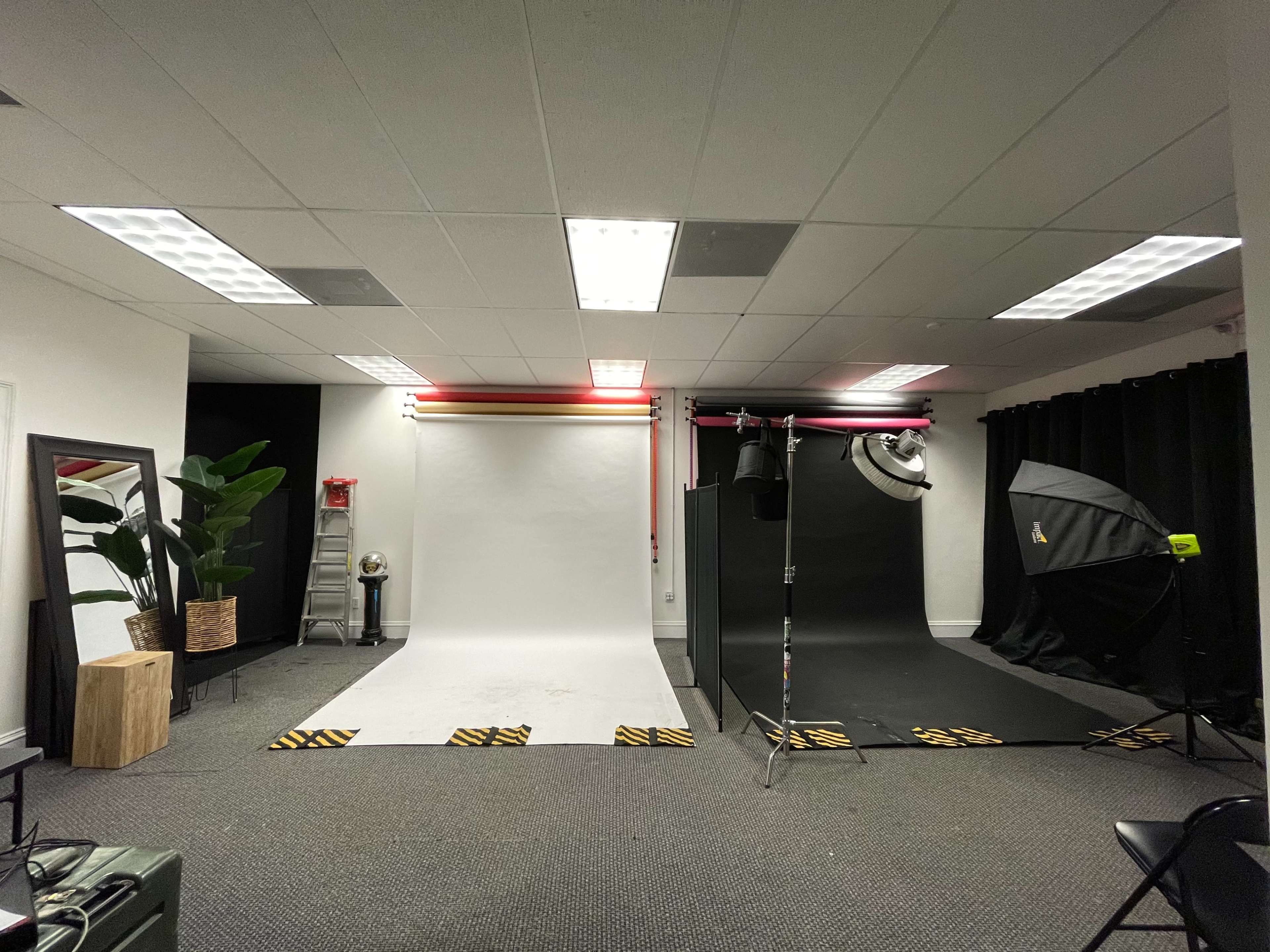 A photography studio featuring two backdrops, one white and one black, with various studio equipment and decorations in the room.