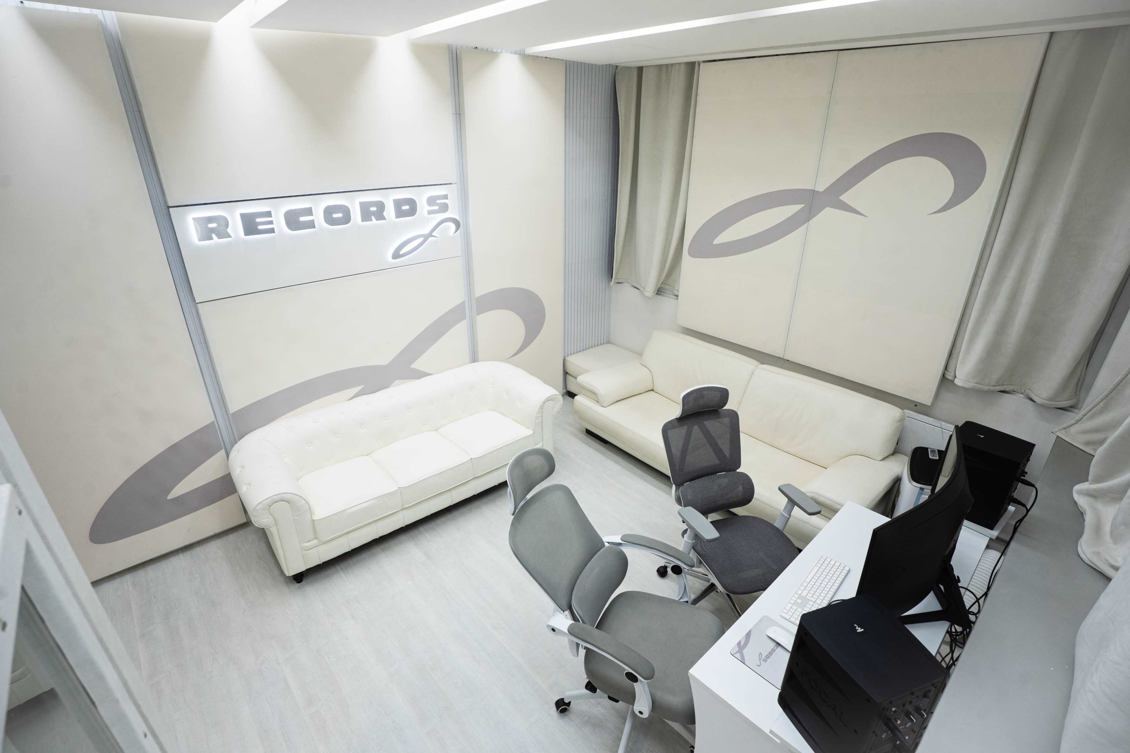 The image shows a modern office space with a white sofa, a gray office chair, a desk with a computer, and "RECORDS" displayed on the wall.