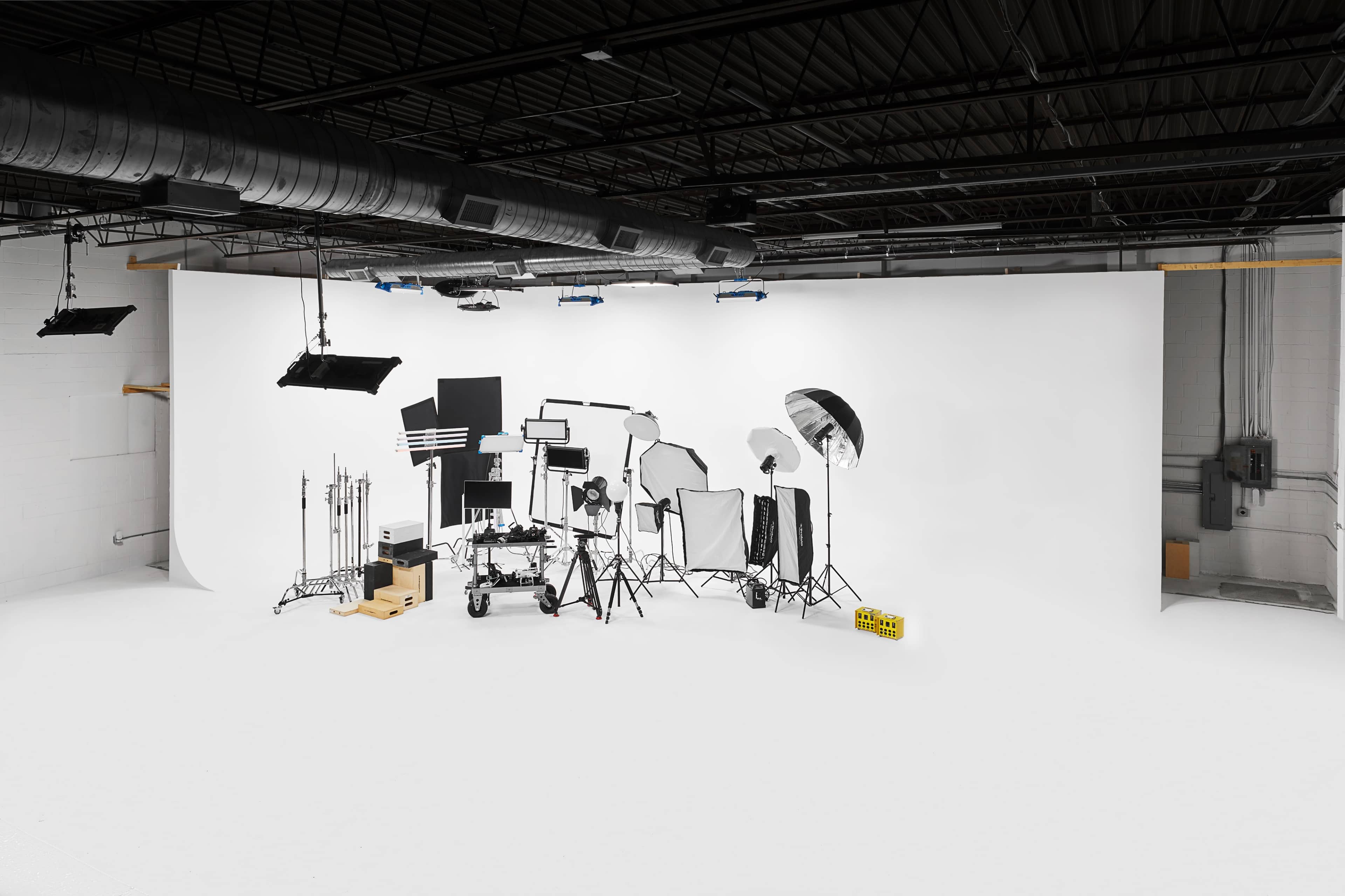 A photography studio equipped with various lighting and camera equipment arranged against a white backdrop.