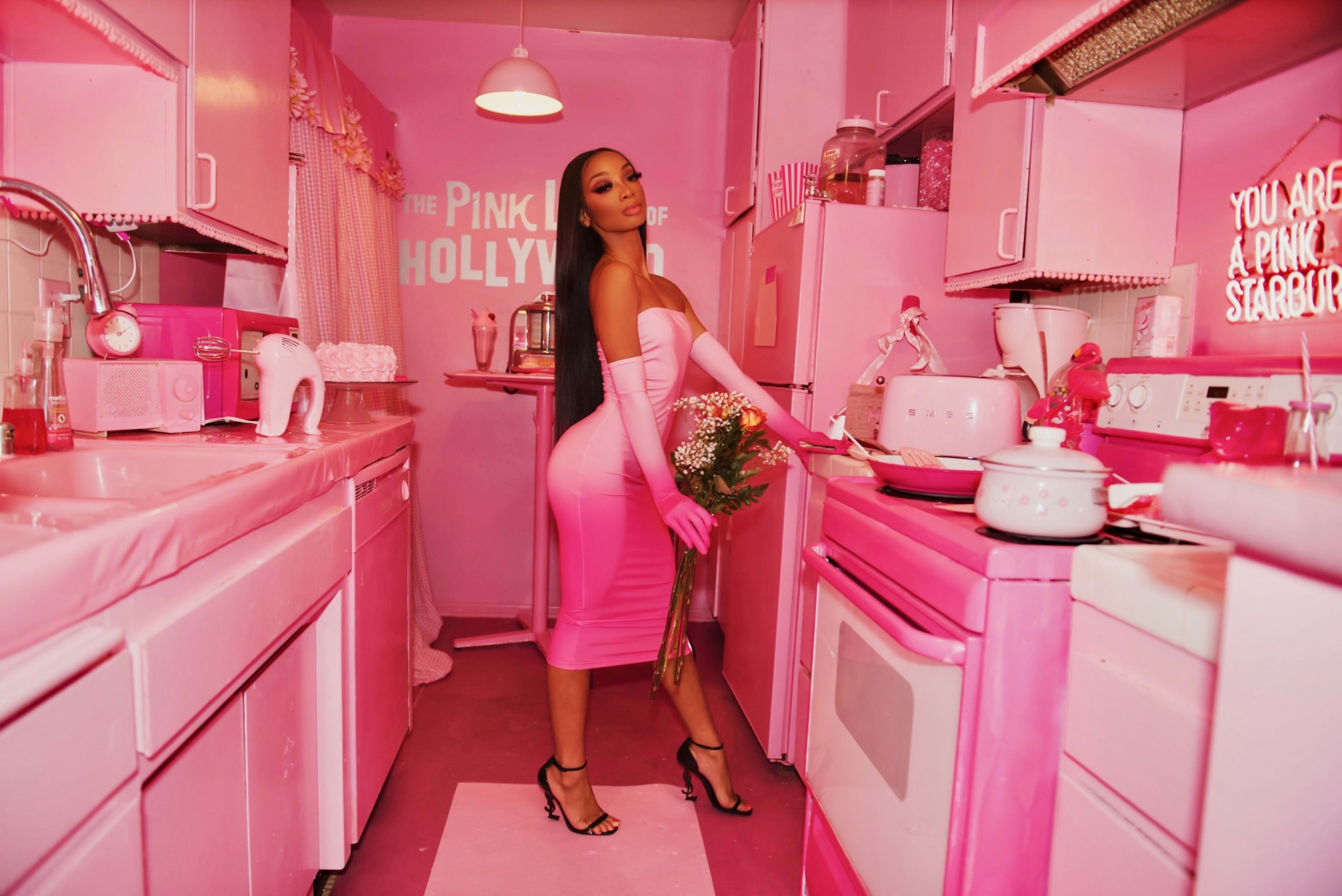 A woman in a pink kitchen with pink appliances for a Hollywood photoshoot.