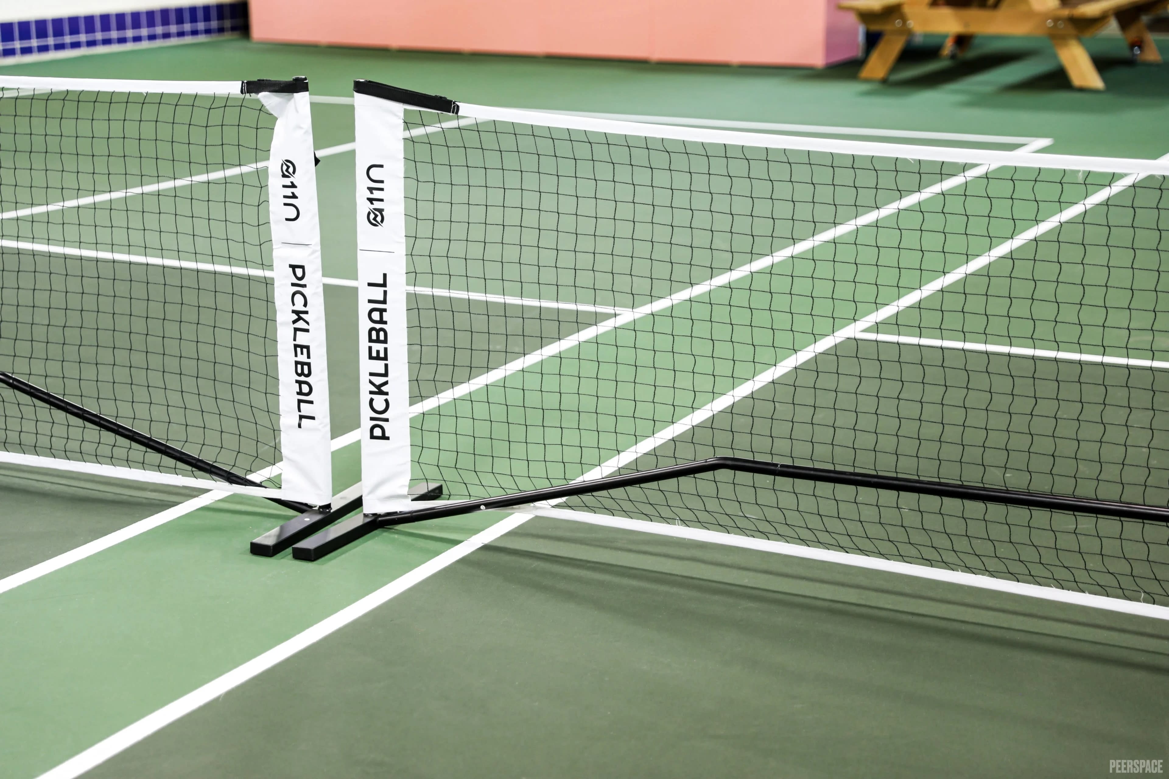 The image shows a pickleball court featuring a net positioned in the center, with marked lines on a green playing surface.