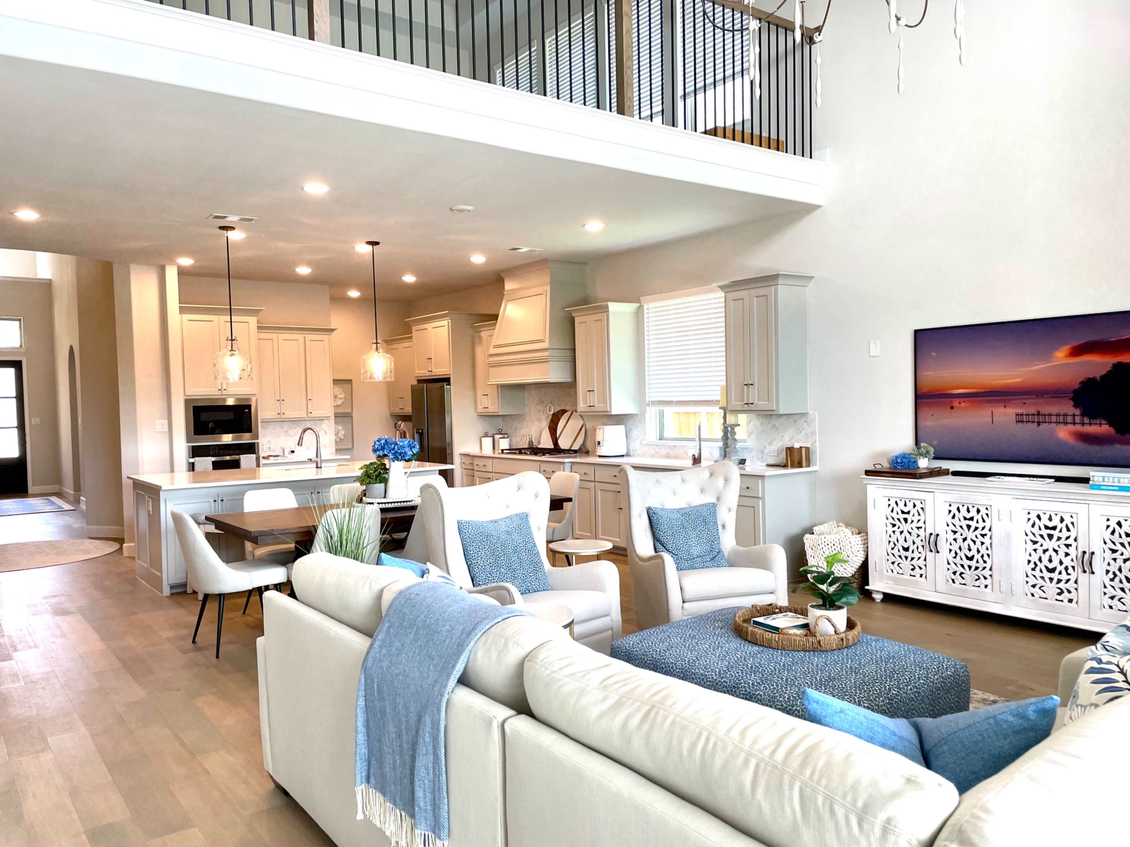 A modern open-concept living area with a kitchen, dining space, and living room, featuring light-colored cabinetry and furniture.