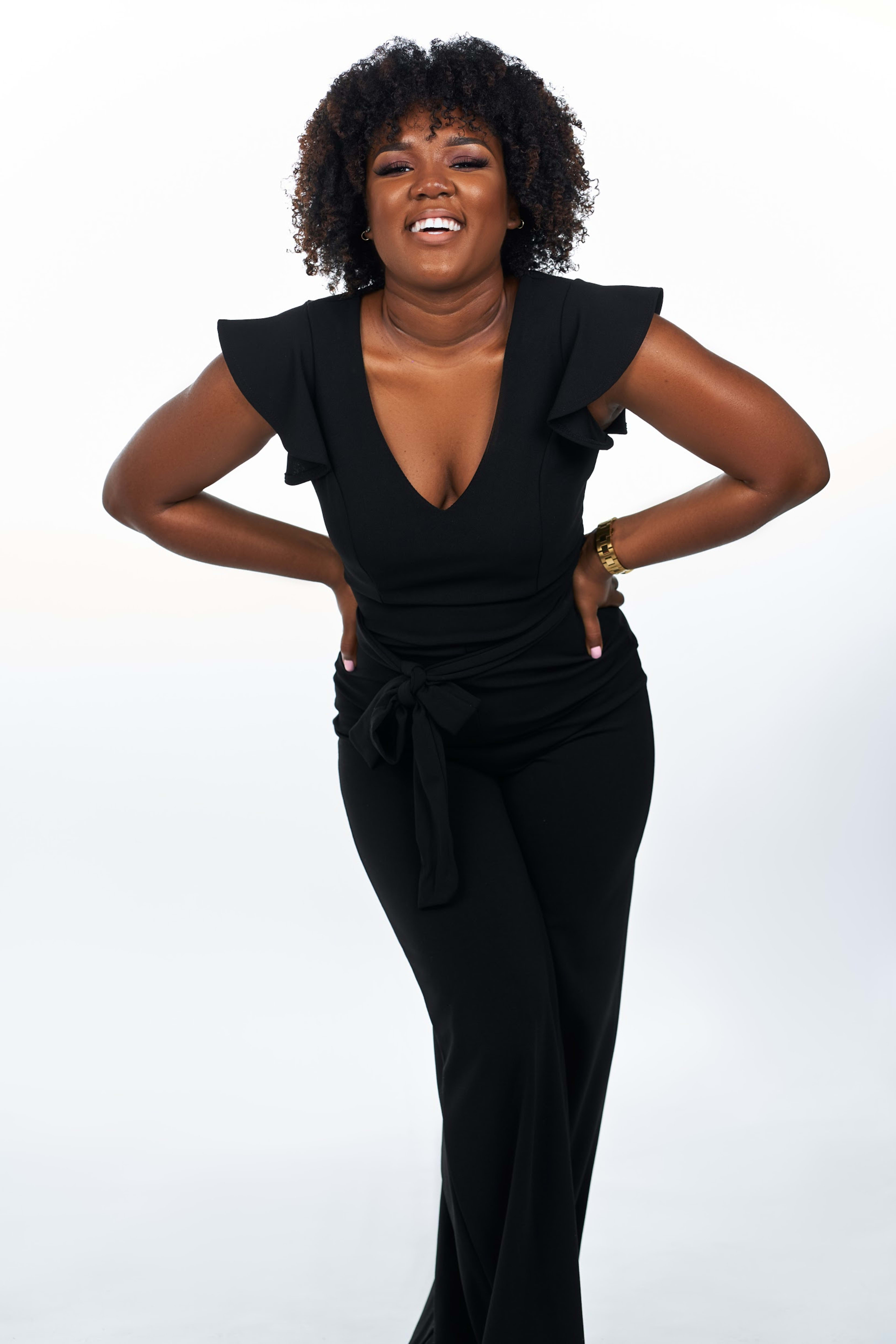 A woman in black dress striking a pose during a fashion photo shoot.