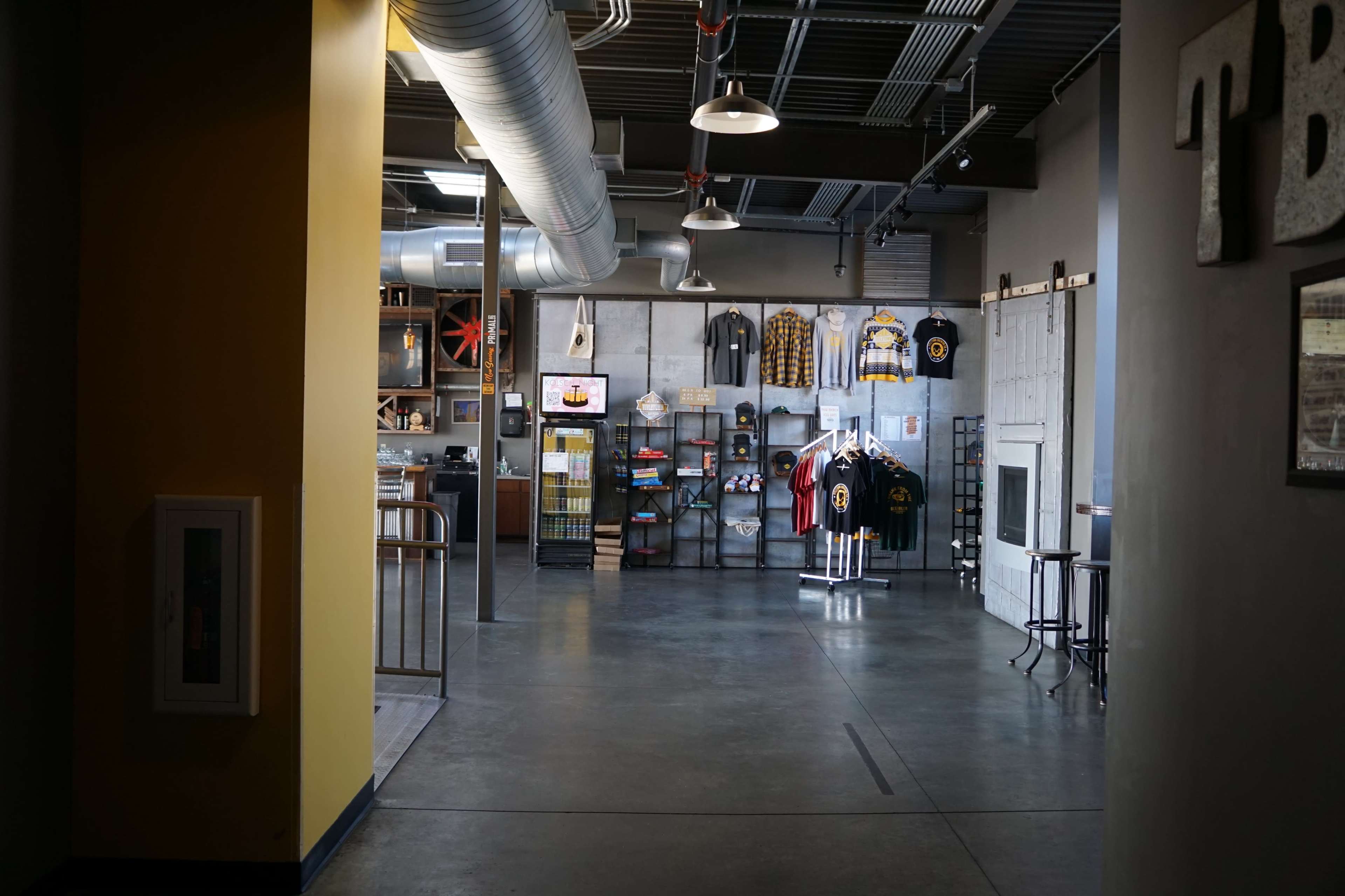 An interior space with display racks of merchandise, a counter area, and exposed ductwork along the ceiling.