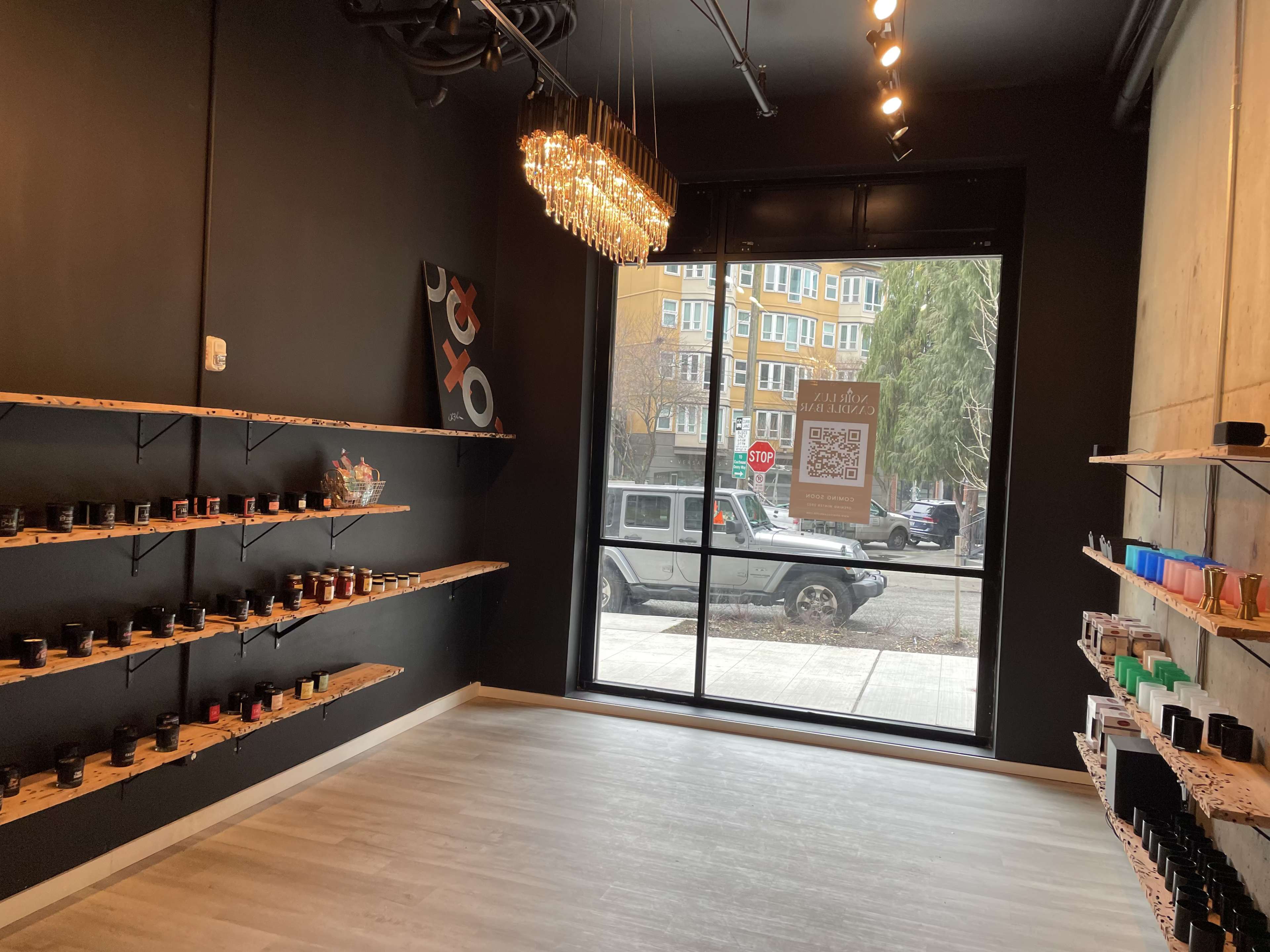 The interior of a store features black walls, wooden shelves lined with jars, and a large window displaying a street view outside.