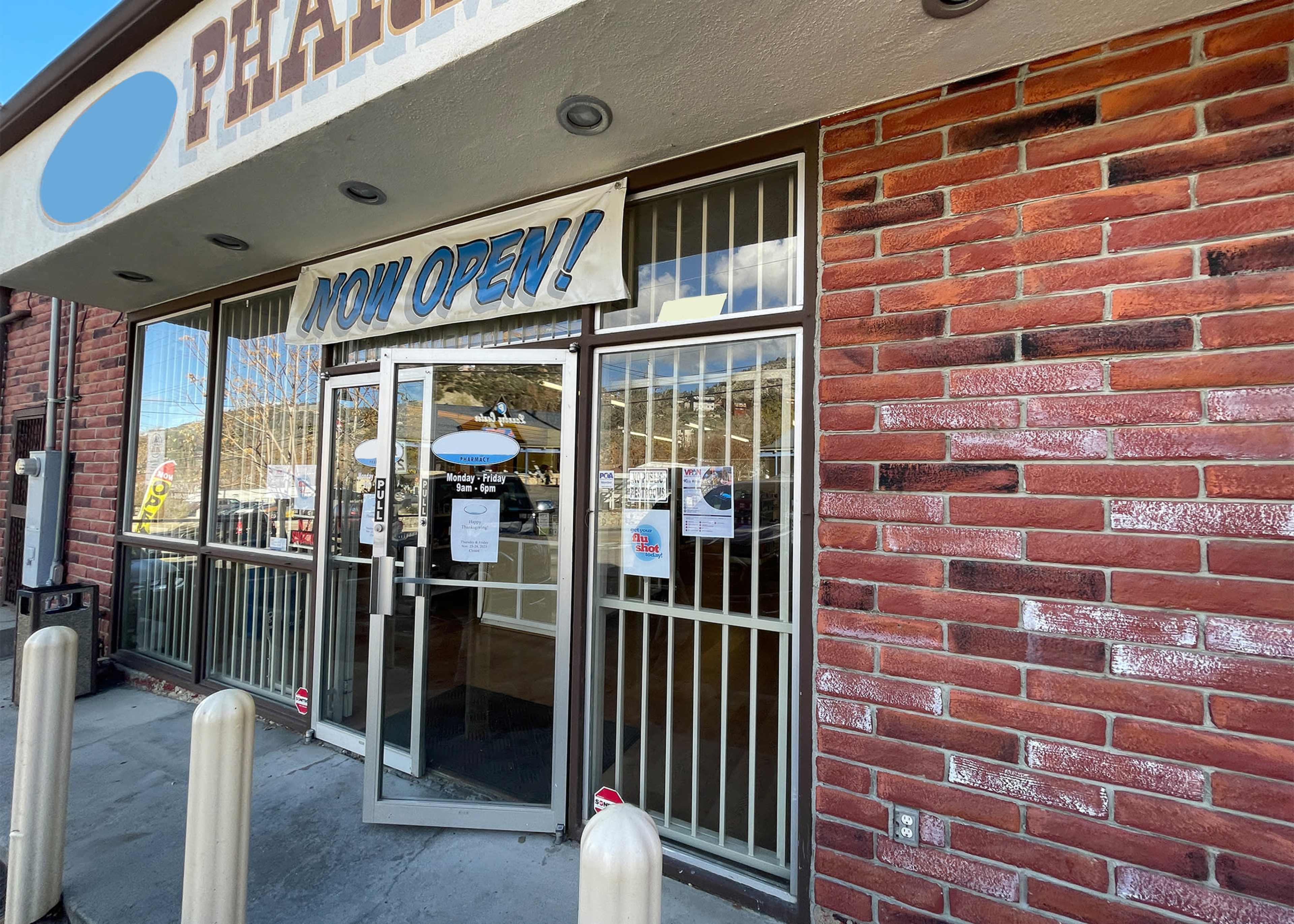 The entrance to a newly opened business features glass doors with a large "NOW OPEN!" signage displayed prominently.