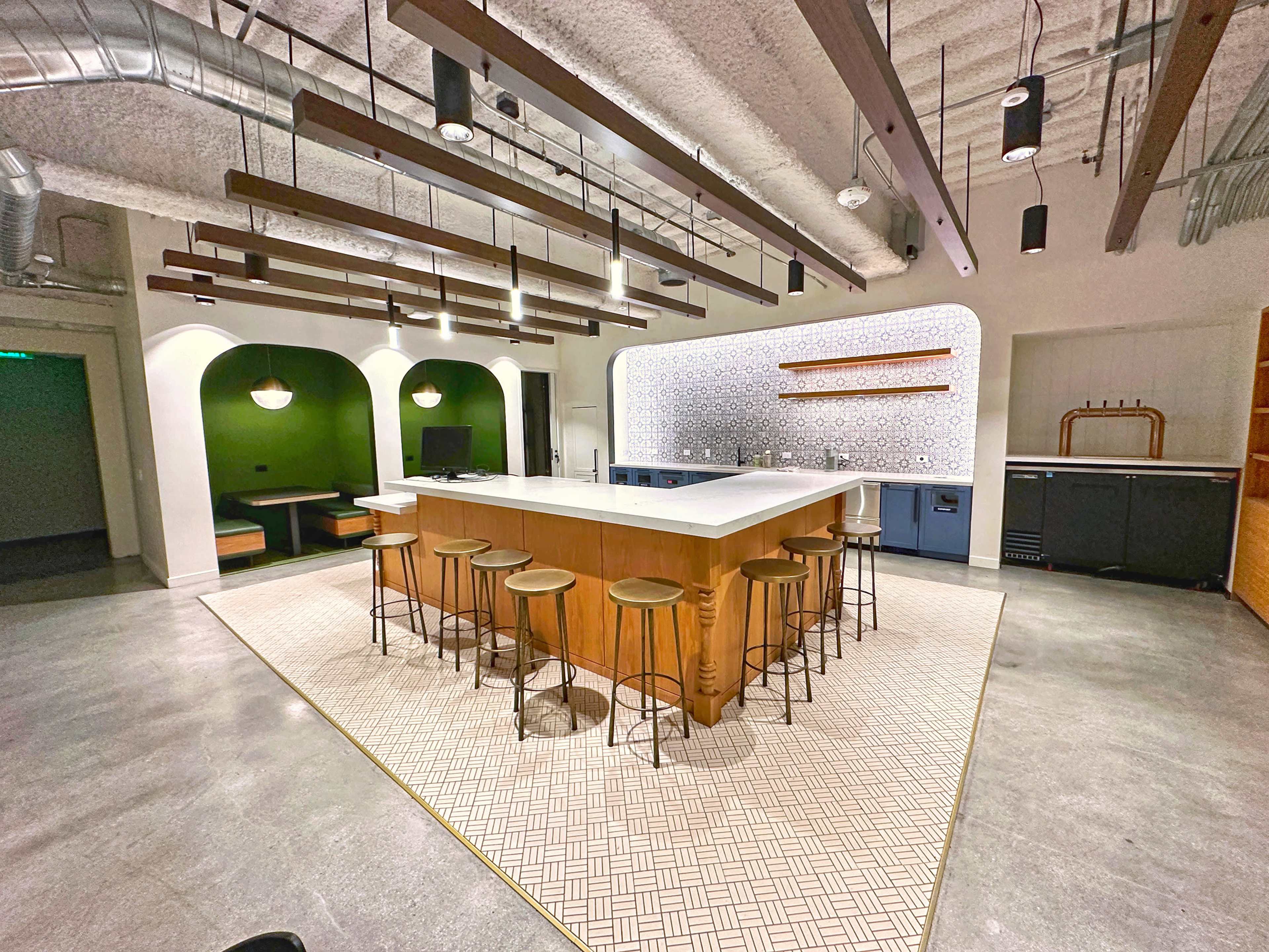 A modern kitchen space features a central island with bar stools, surrounded by various seating areas and decorative elements.