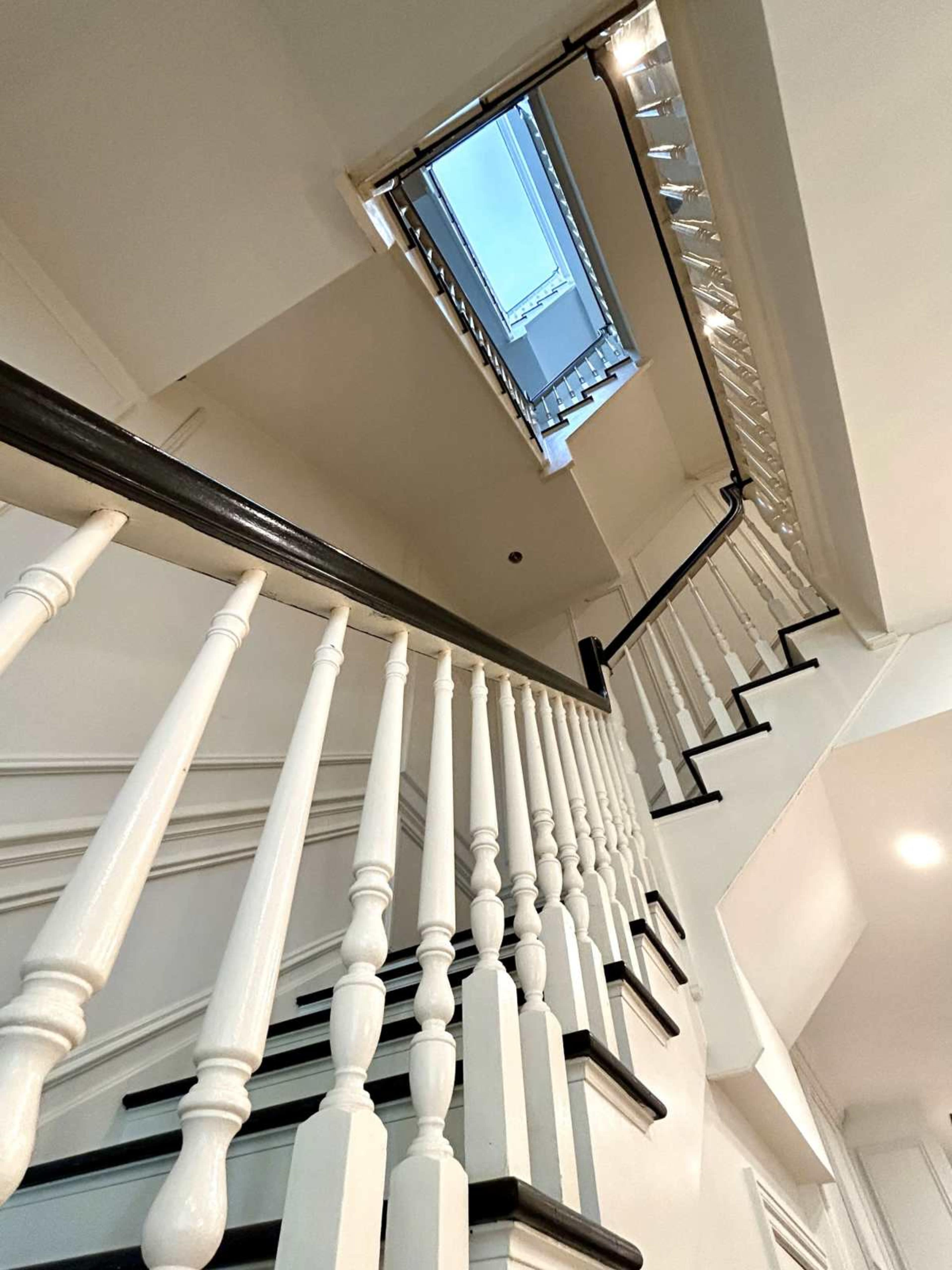 The image shows a spiral staircase with white railings and a skylight at the top.