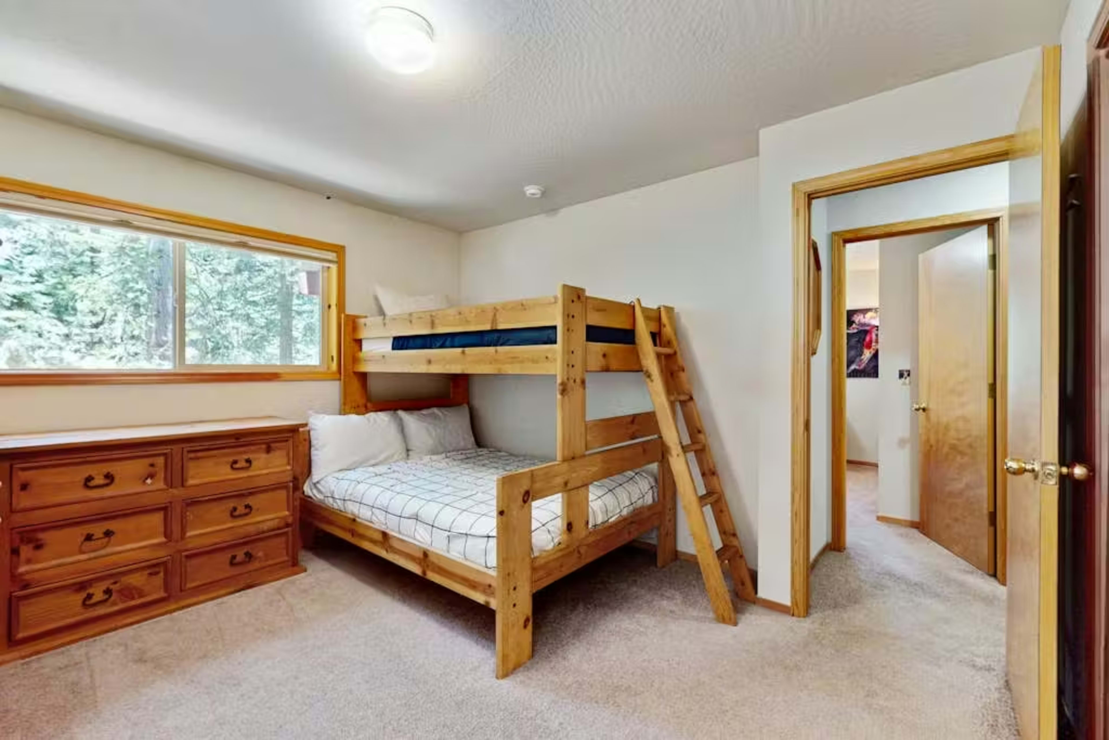 The image shows a bedroom with a wooden bunk bed, a dresser, and a doorway leading to another room.