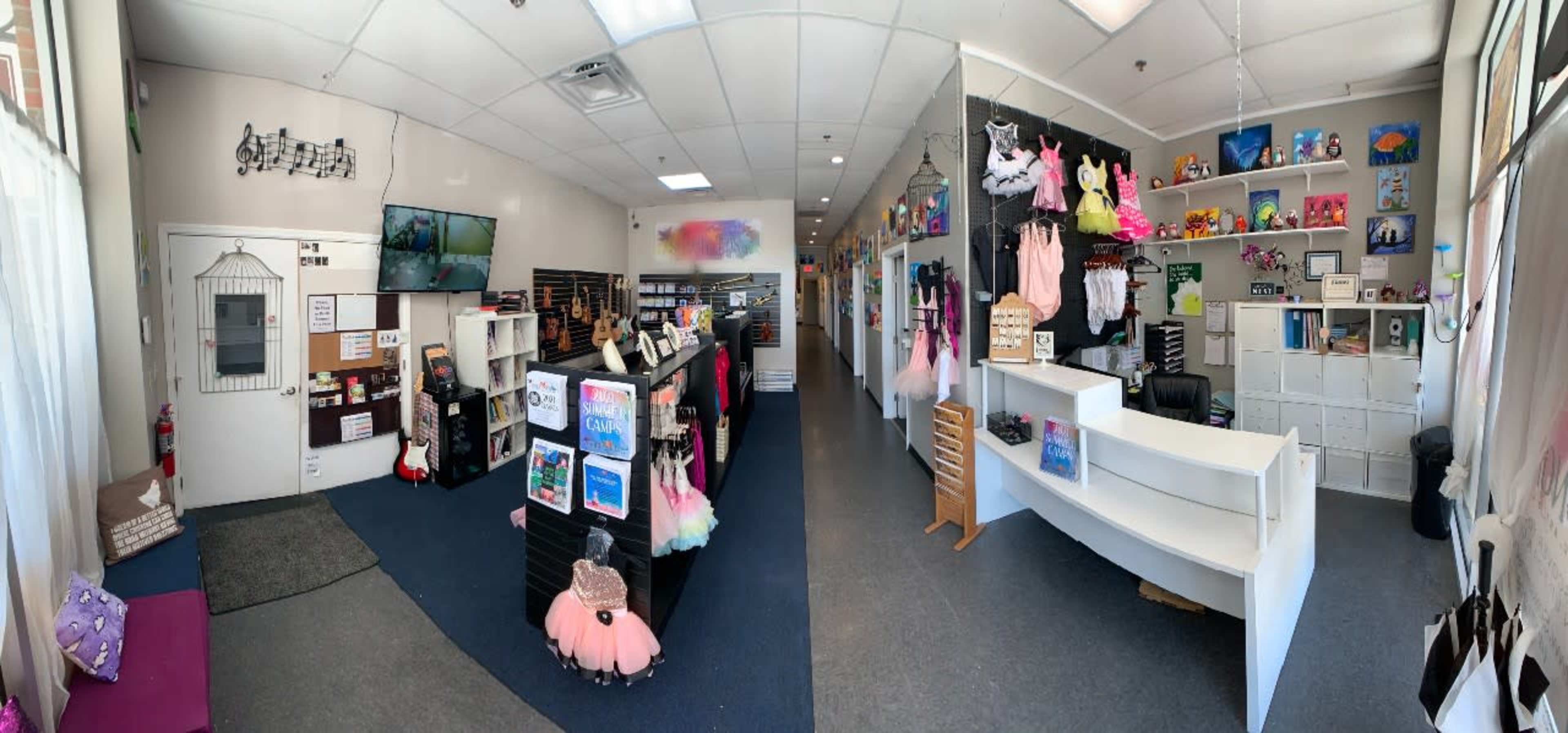 An interior view of a shop with a reception area, decorated walls, organized displays of clothing and accessories, and a seating area.