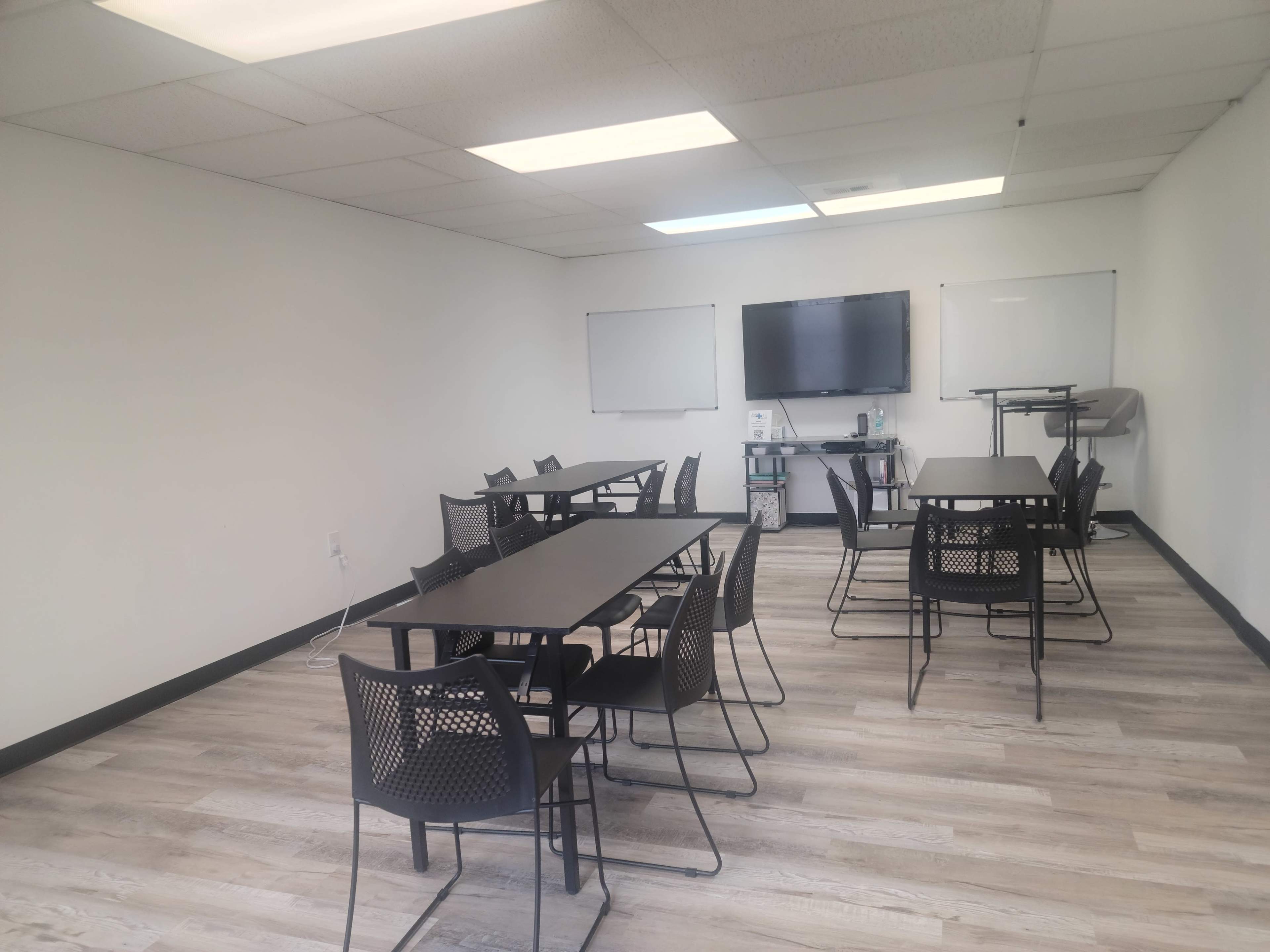 A light-filled meeting room features several tables and chairs arranged for group discussions.