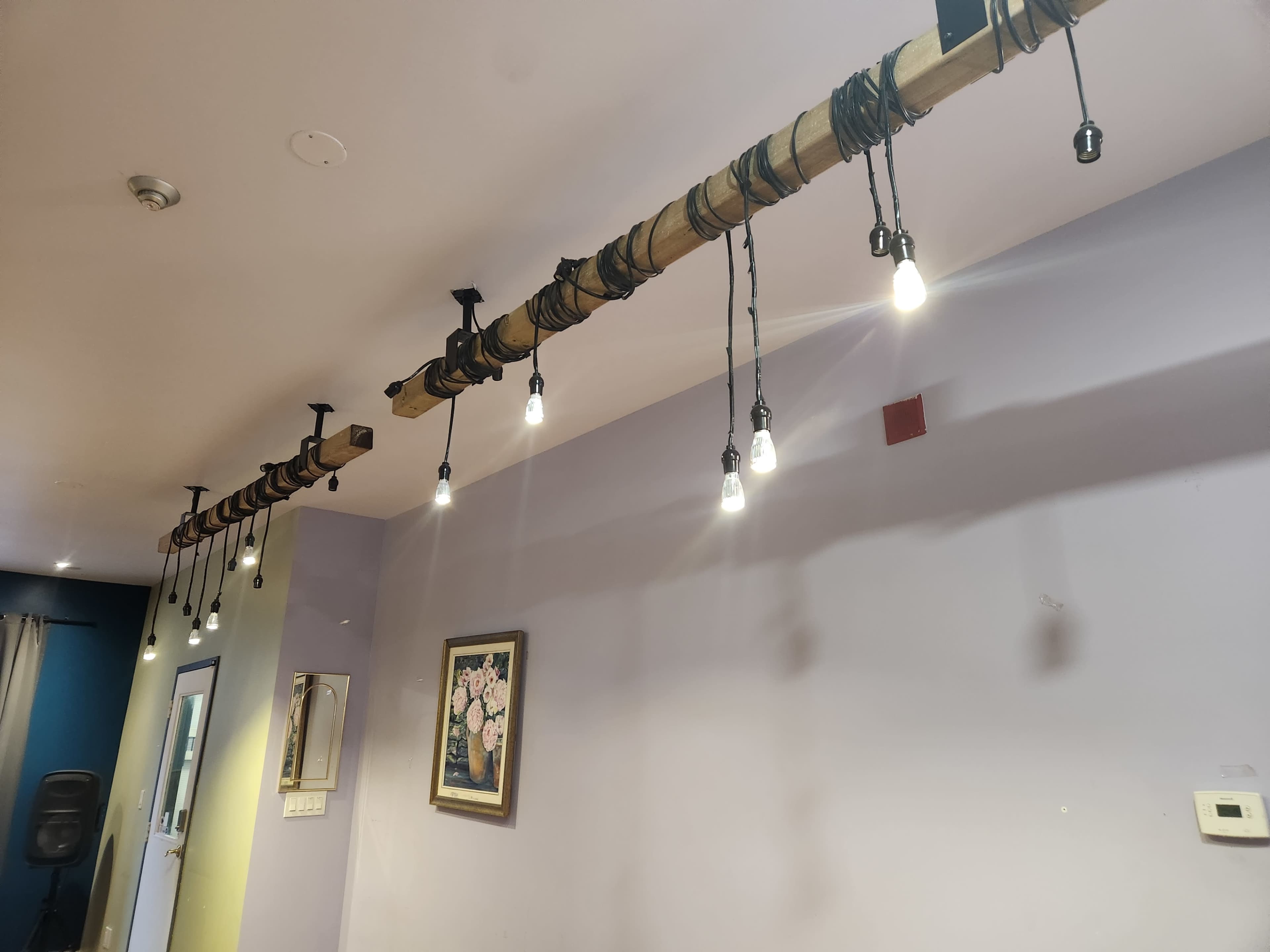 A row of pendant lights hanging from a wooden beam attached to the ceiling.