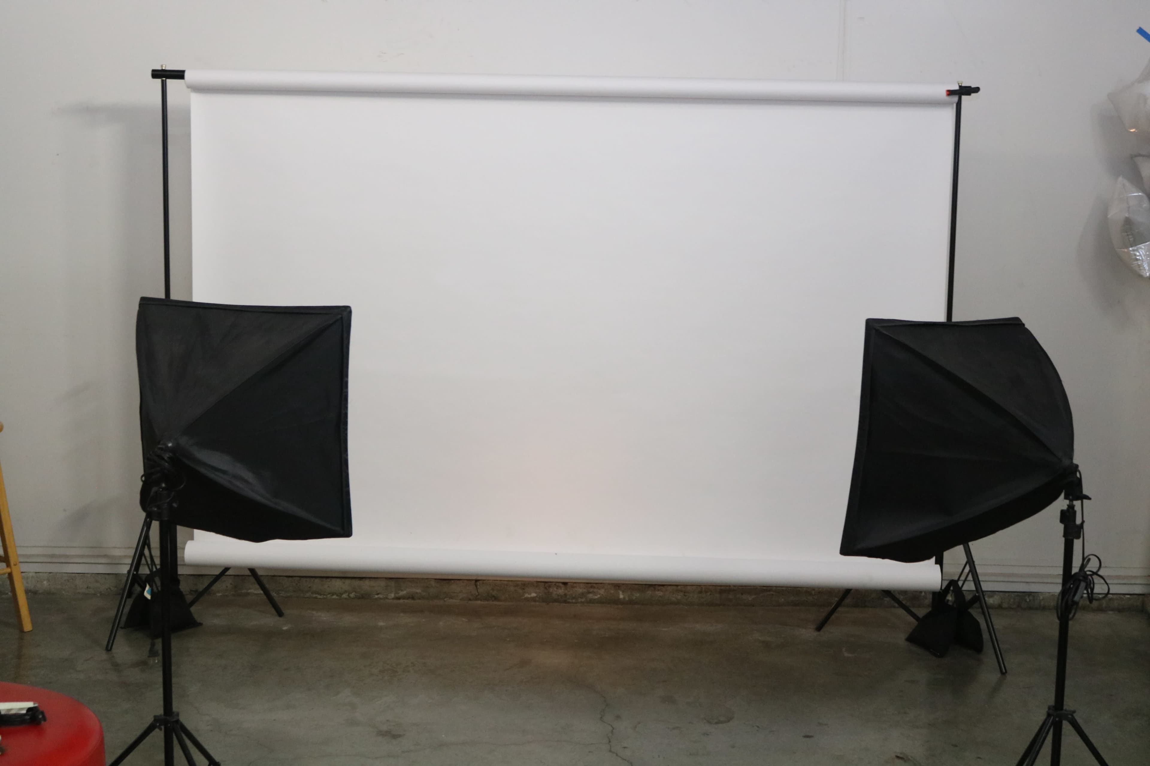 A blank white backdrop set up between two softbox lights in a studio space.
