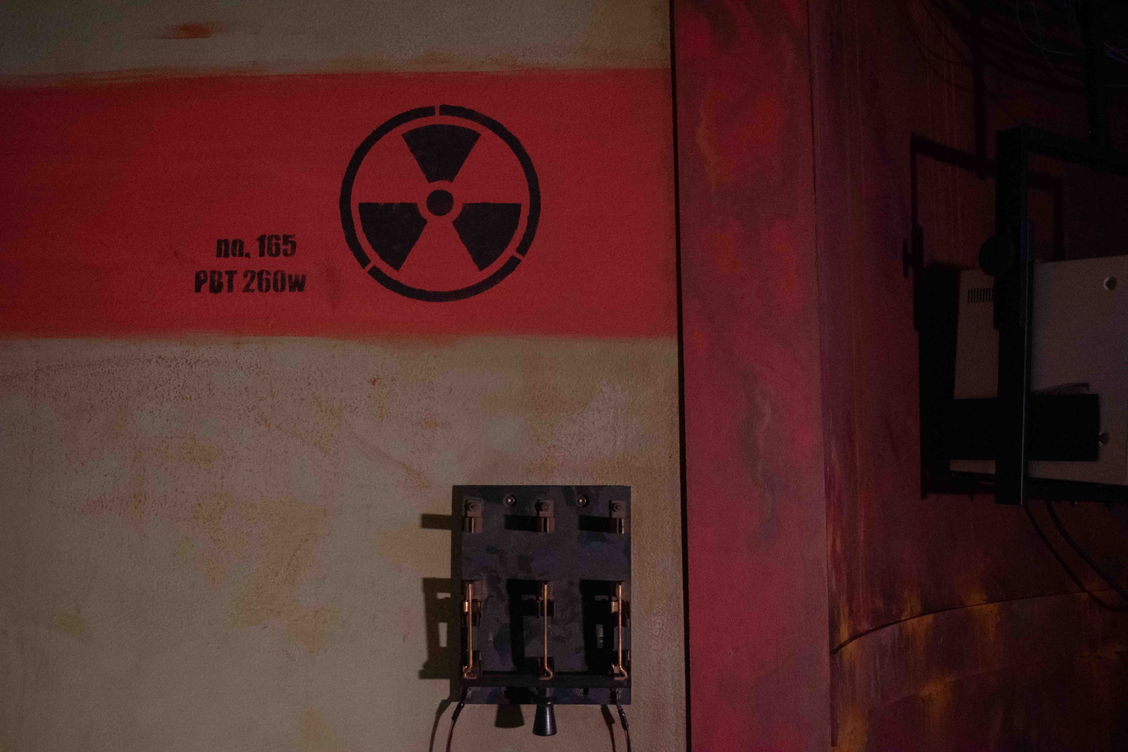 A wall with a radiation symbol and a panel of switches mounted beside it.