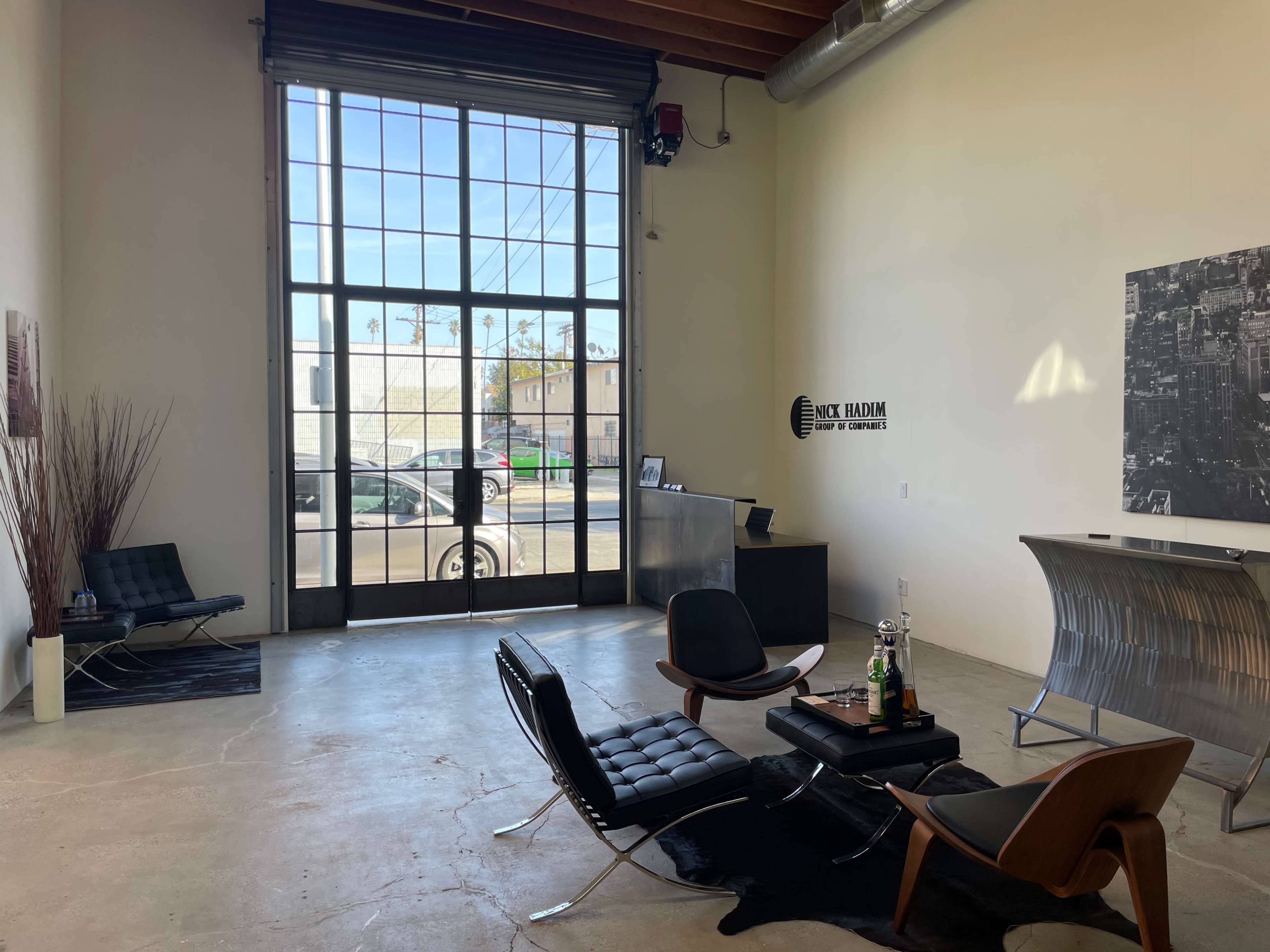 The interior of a modern office space features sleek furniture, a reception desk, and large windows allowing natural light to flood the area.