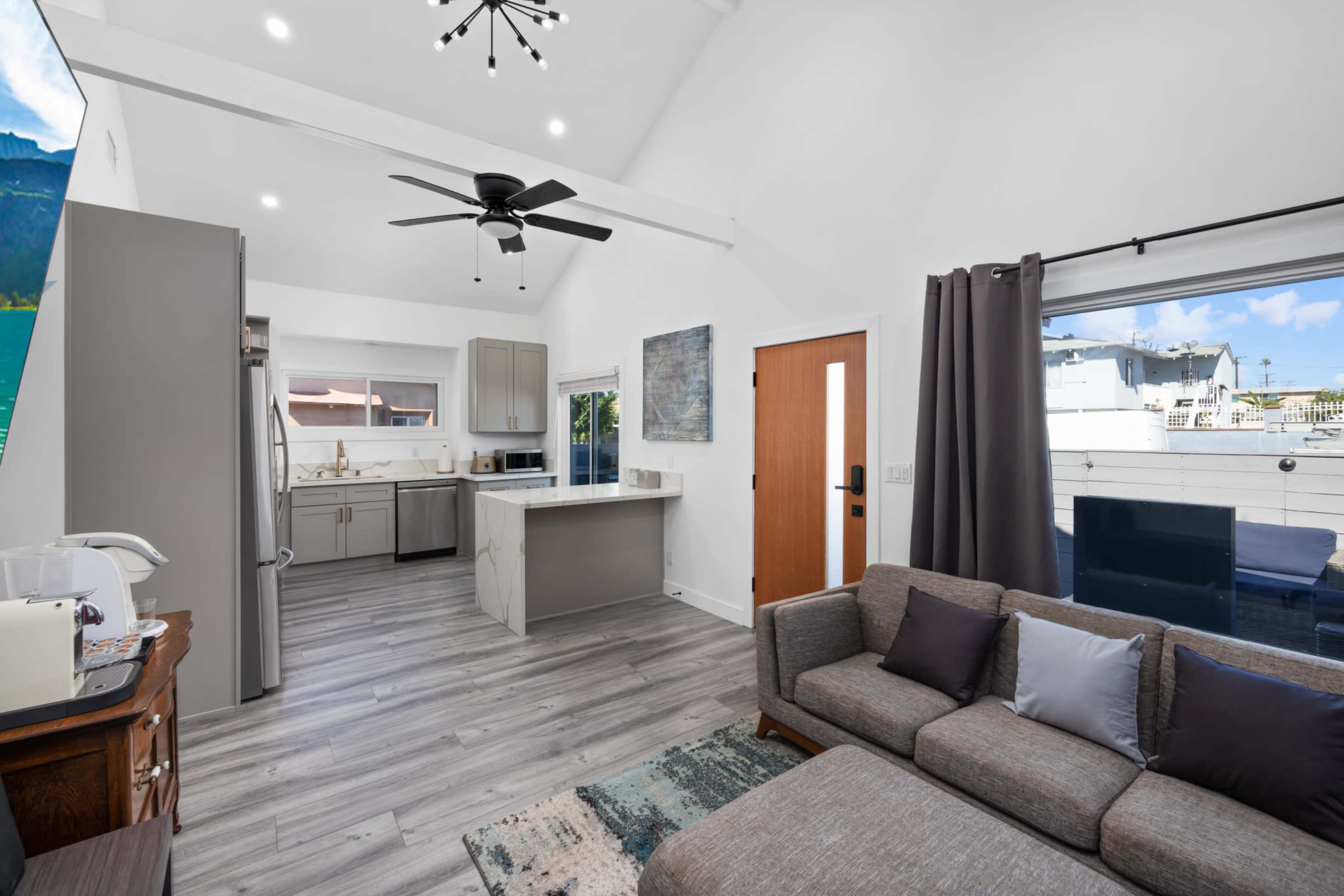 A modern, open-concept living space featuring a kitchen, dining area, and a seating area with a sofa.