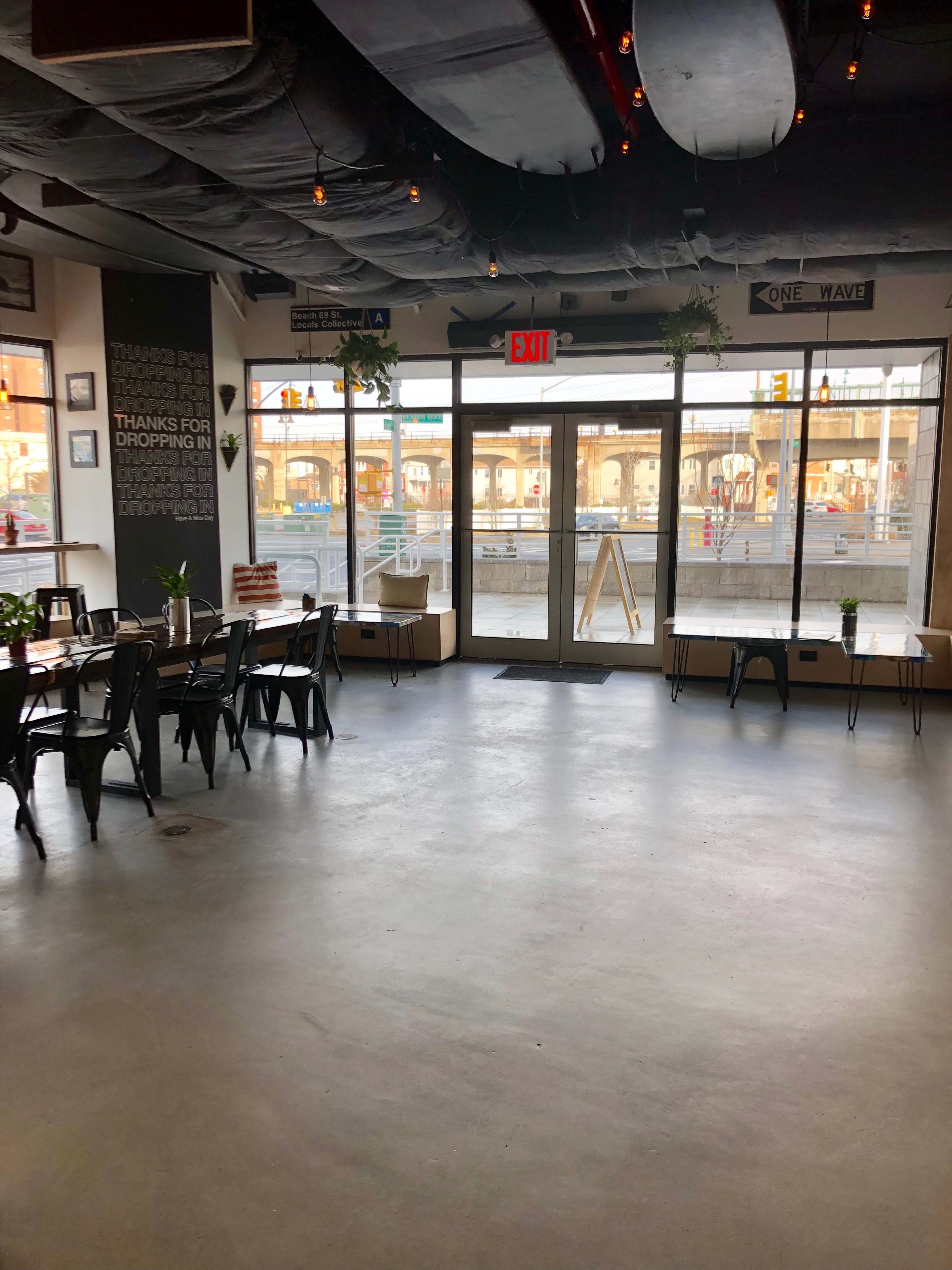 The image shows a spacious café interior with seating arrangements and large glass doors leading to an outdoor area.