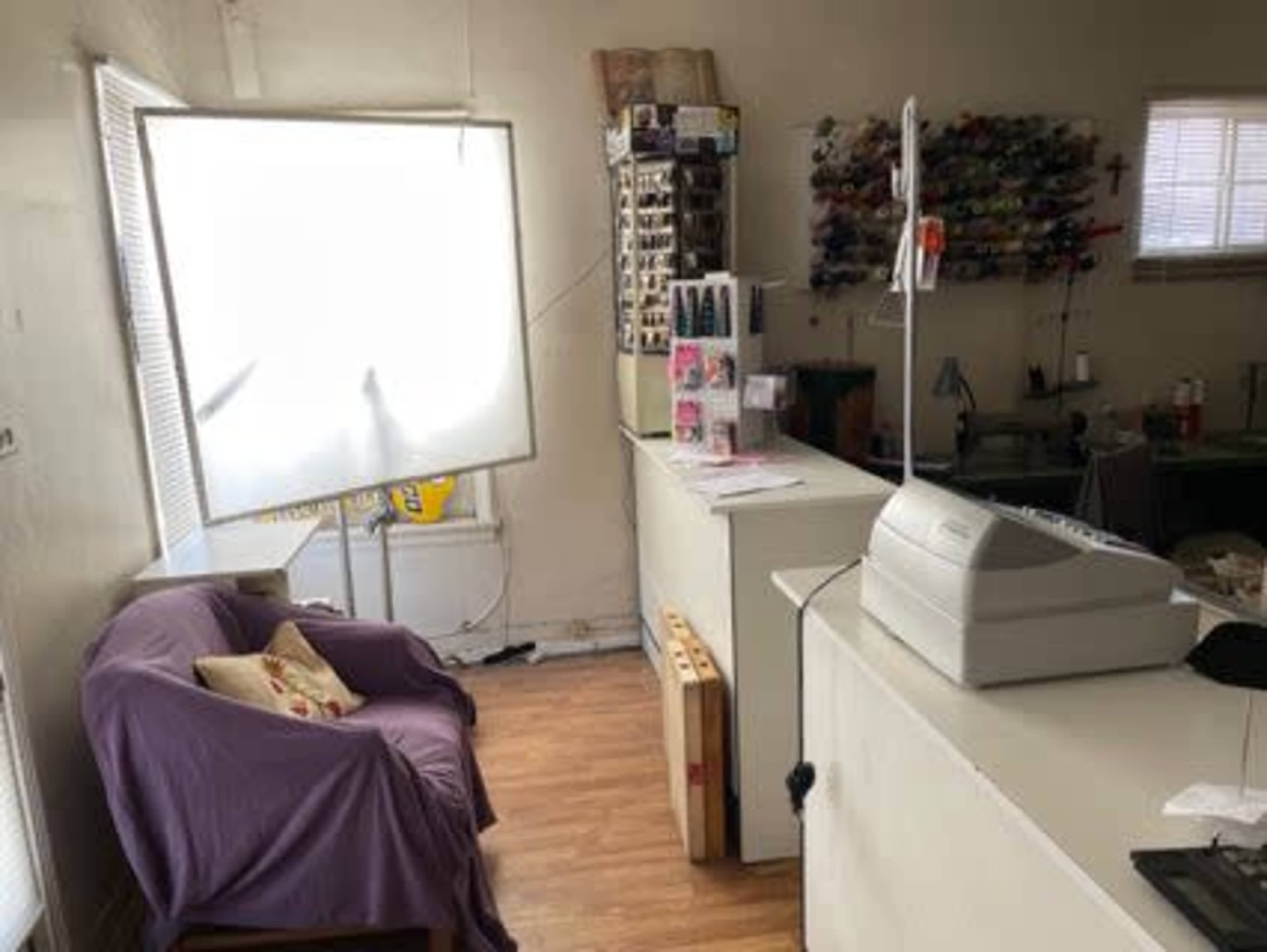 The image shows an interior space with a purple couch, a counter with a cash register, and a large softbox for lighting.