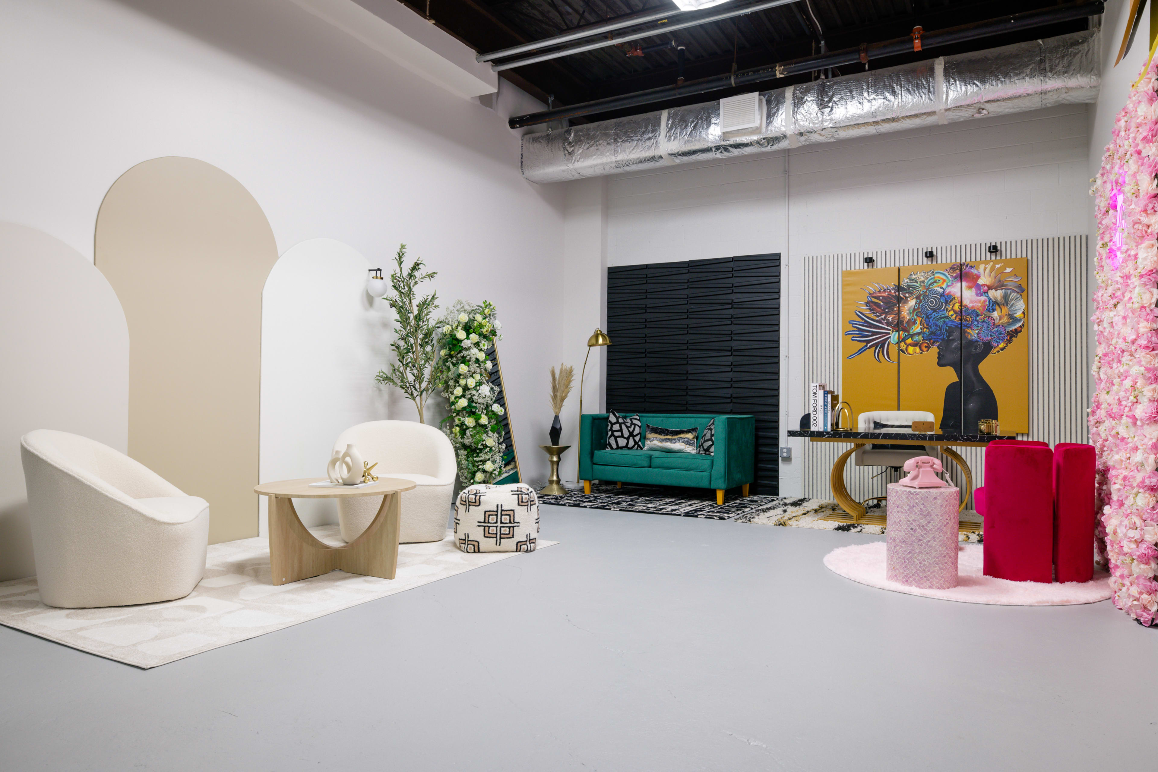 A modern interior space featuring a seating area with two chairs, a table, decorative plants, and art on the walls.