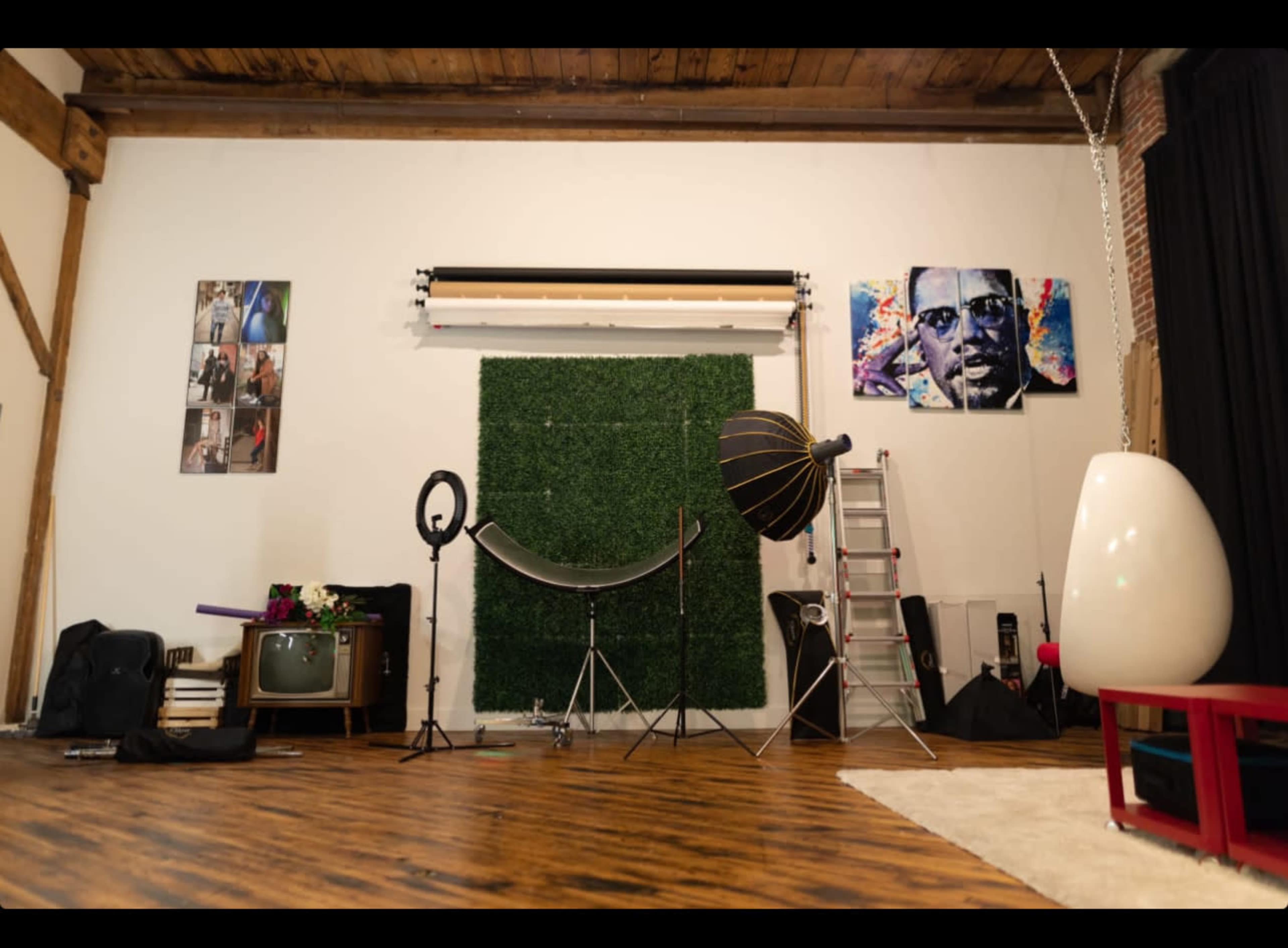 A photography studio with a green wall, various lighting equipment, props, and a ladder.