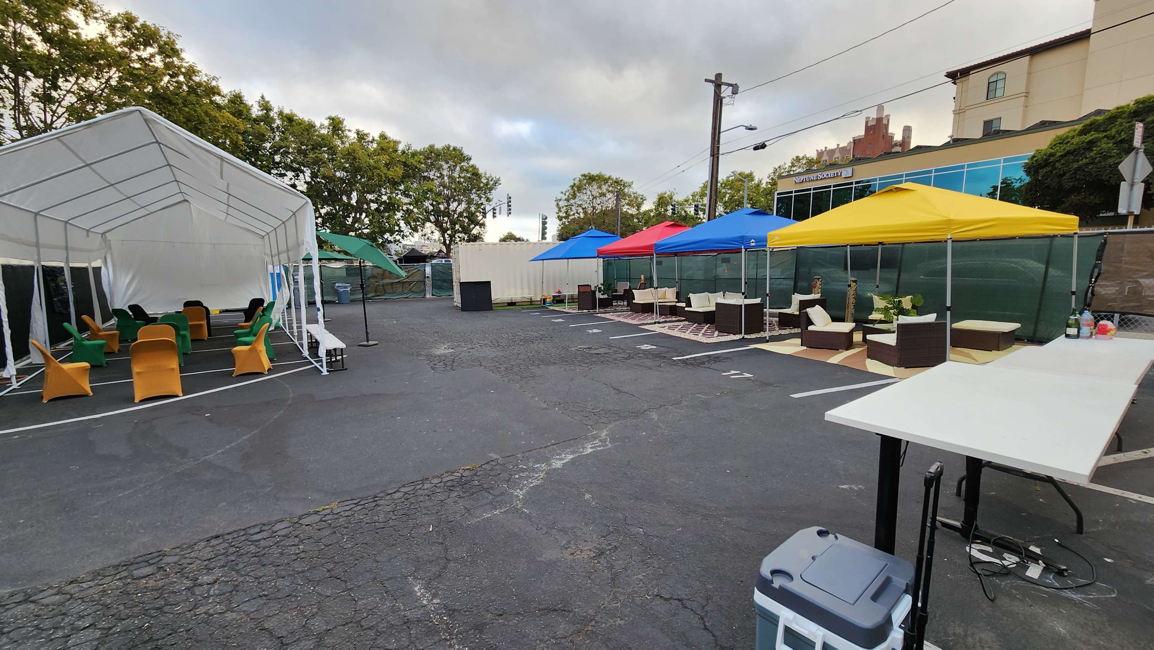 An outdoor event space with several tents, colorful canopies, and seating arrangements set up in a paved area.