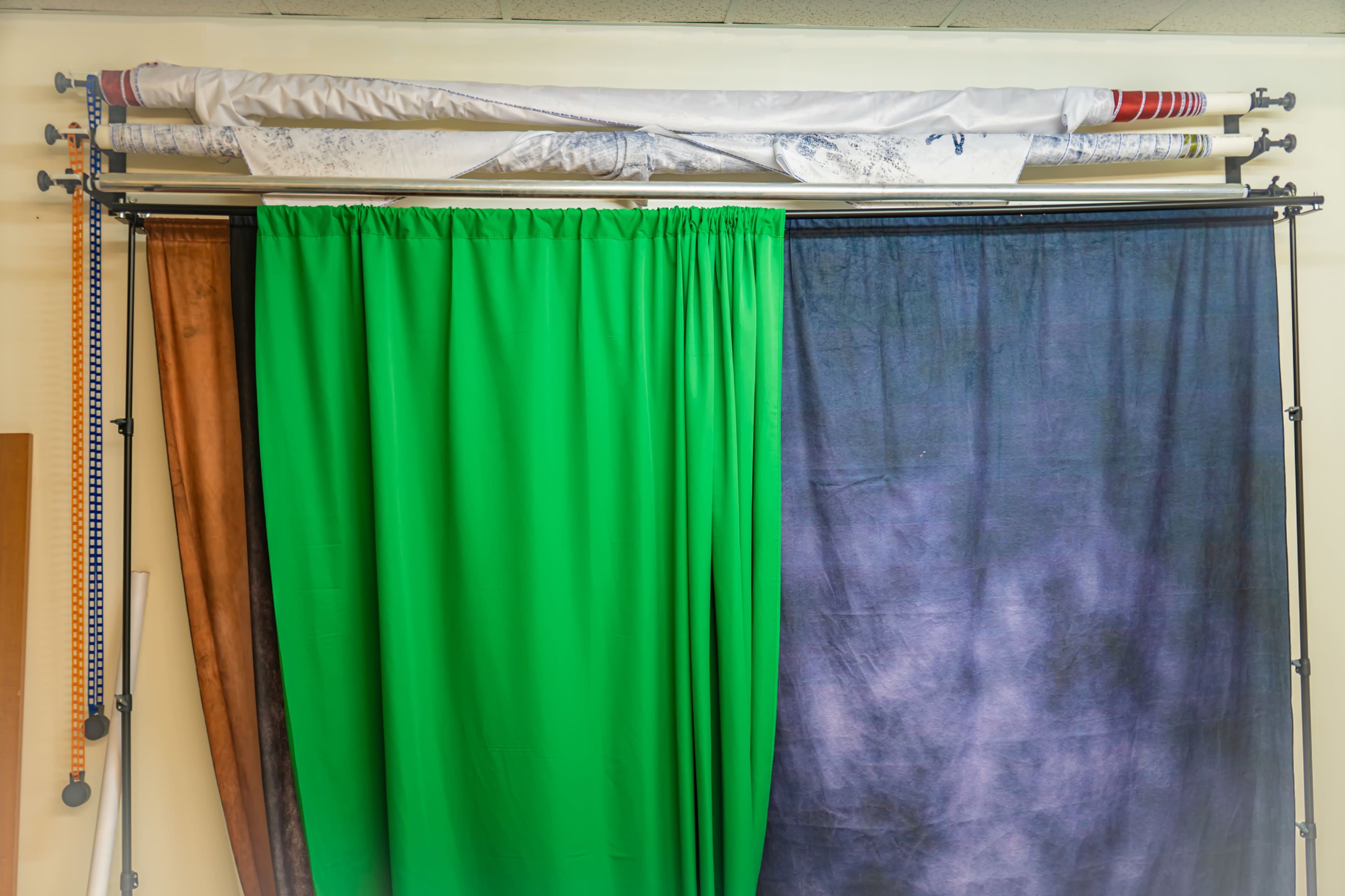 A set of fabric curtains in various colors hanging from a rack against a wall.