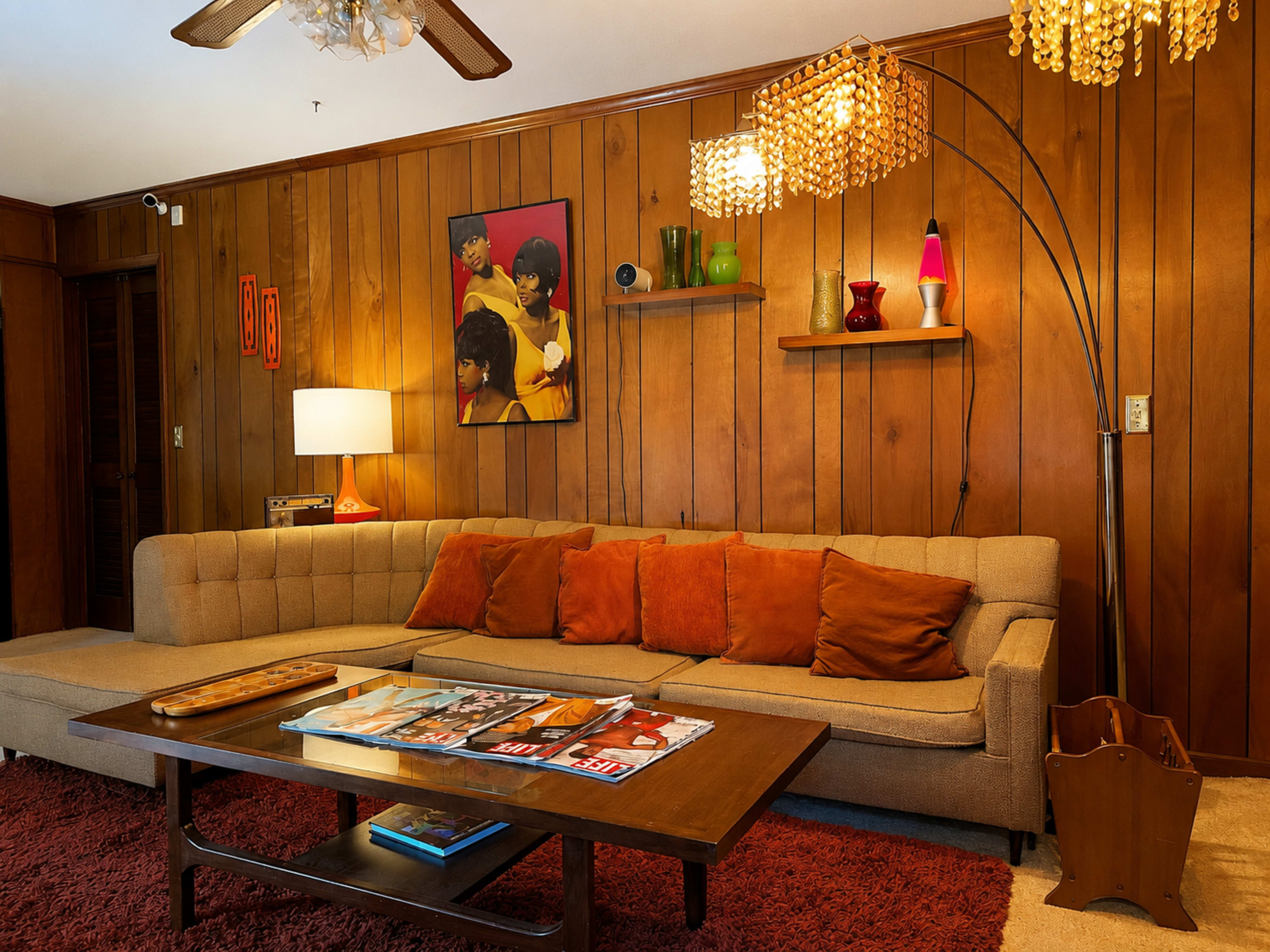The image shows a vintage living room with wooden paneling, a tan sectional sofa, a coffee table displaying magazines, and various decorative lighting fixtures.