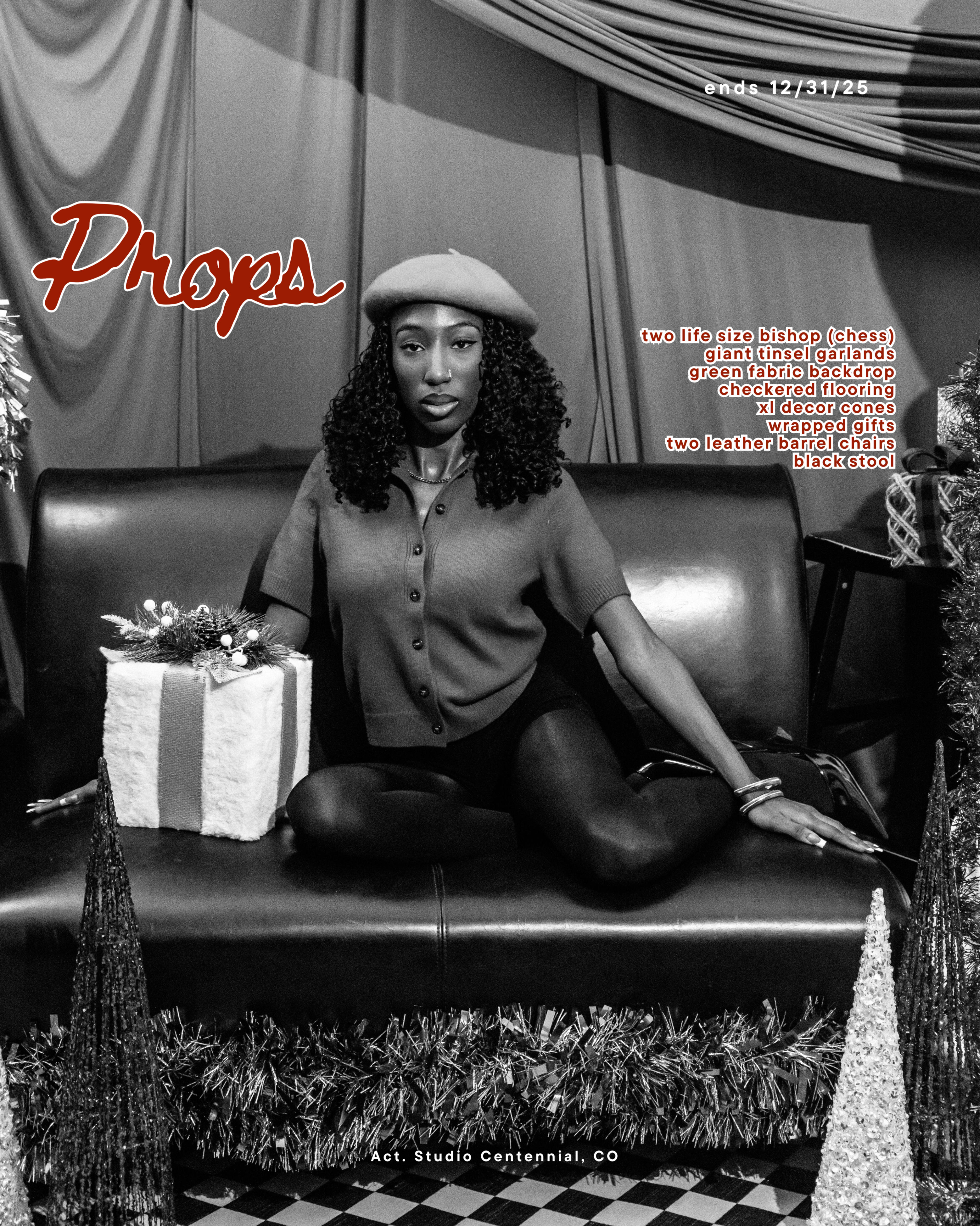 A woman sits on a black sofa in a studio decorated with Christmas trees and a gift, while wearing a gray outfit and a black beret.