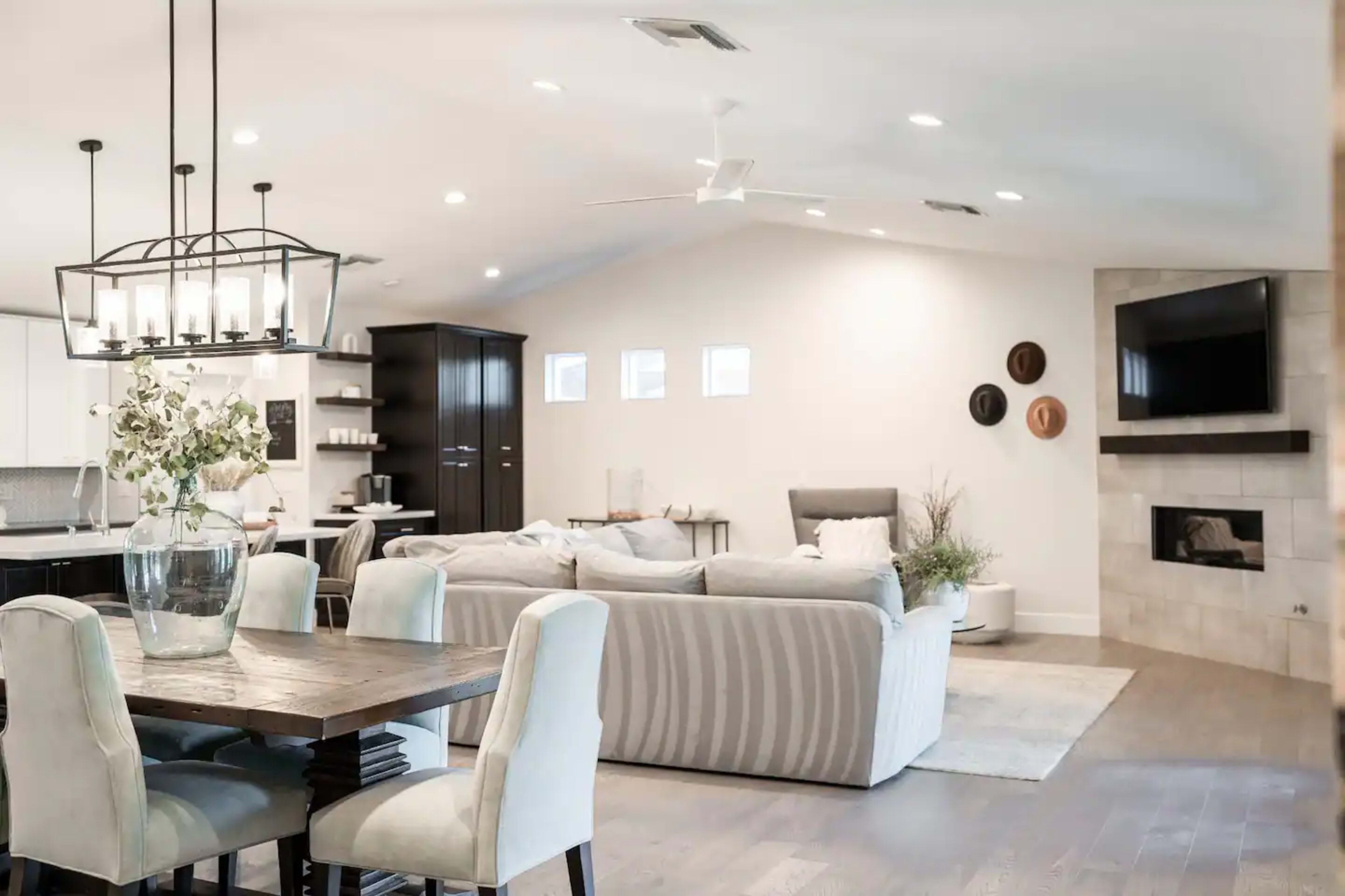 A modern open-concept living and dining area with a wooden dining table, upholstered chairs, a cozy seating arrangement, and a fireplace.