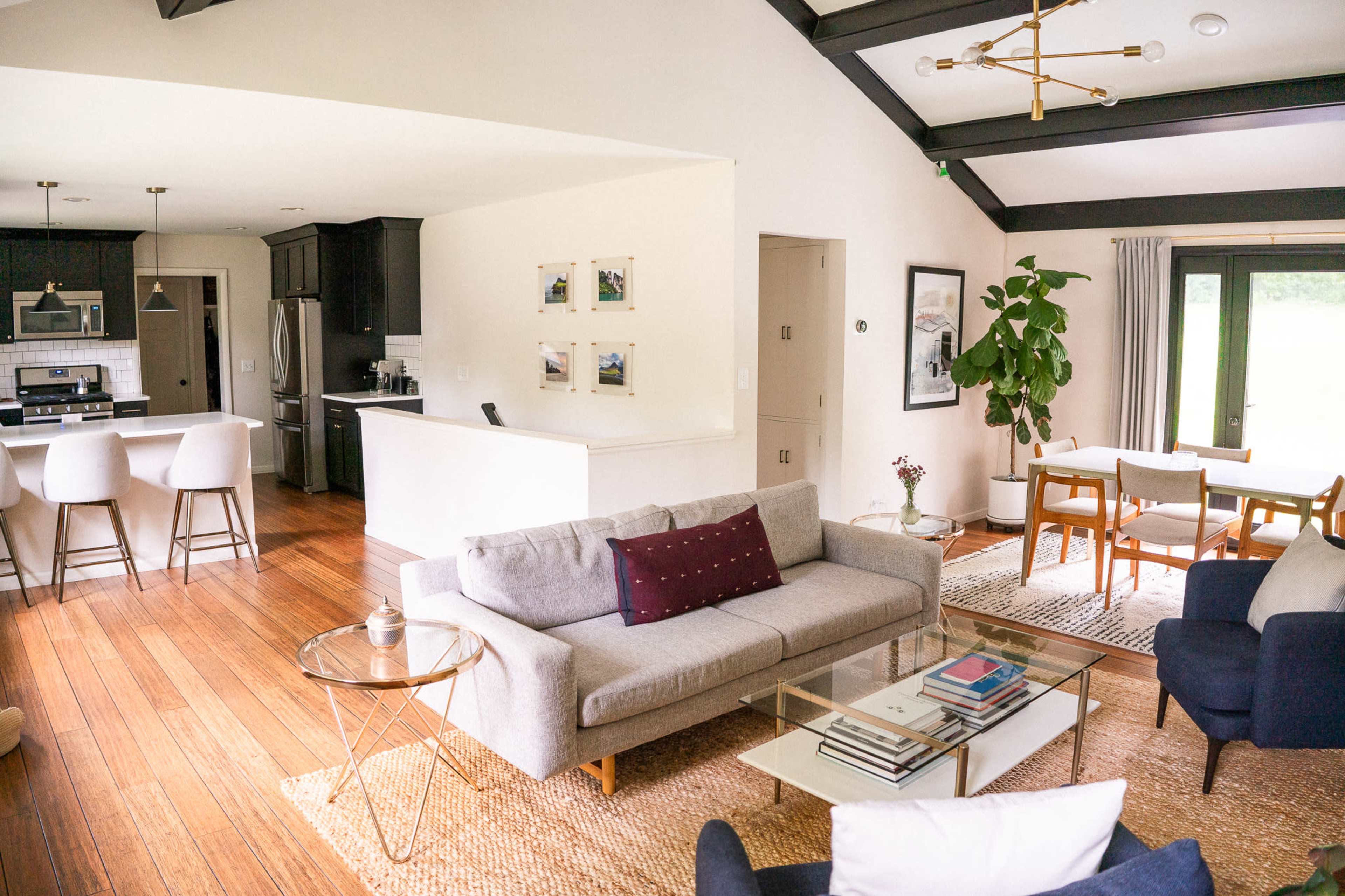 An open-concept living space featuring a modern living room with a gray sofa, coffee table, and a dining area with wooden chairs and a table.