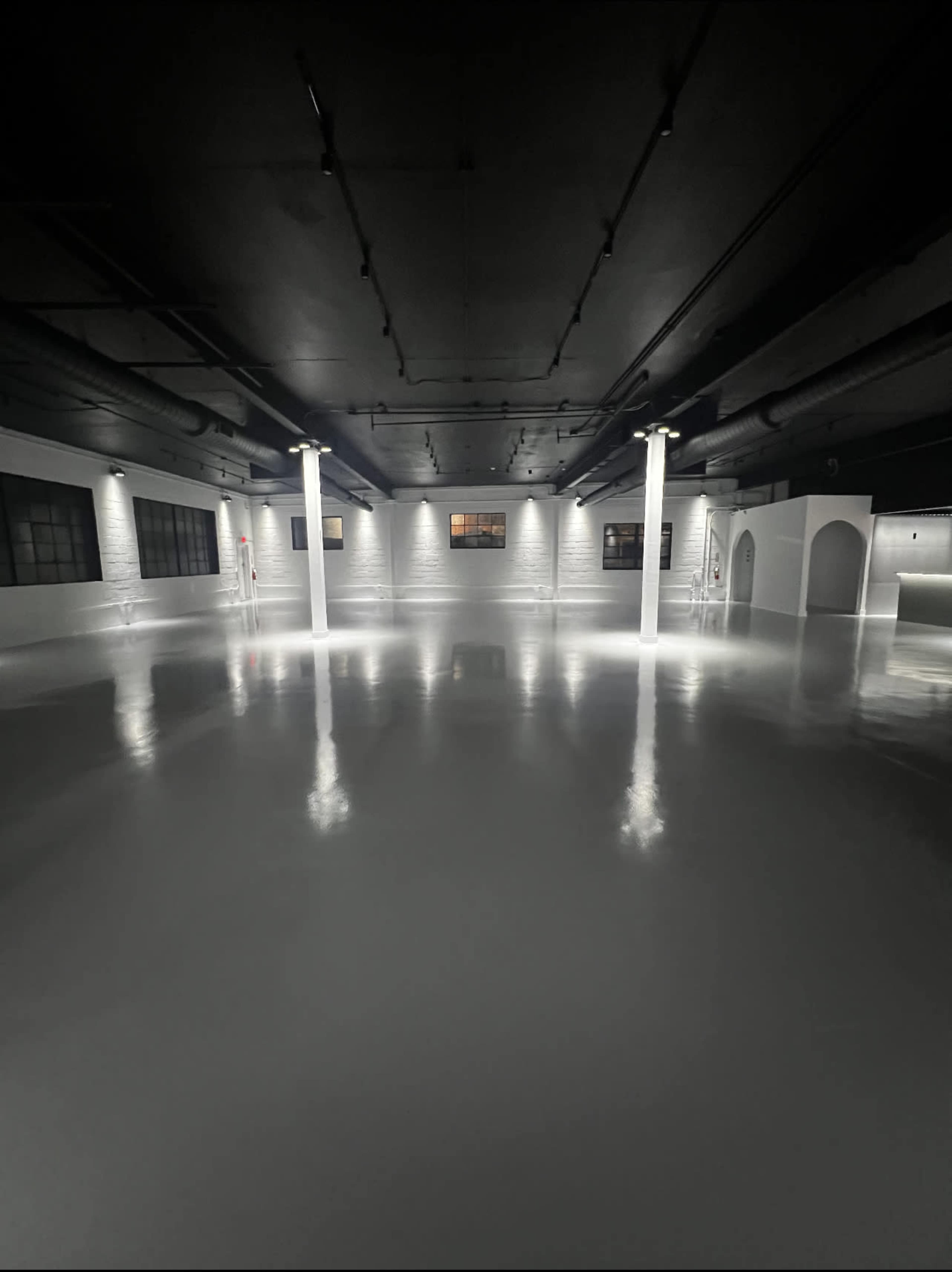 The image shows a spacious, well-lit industrial room with a glossy floor and polished white walls.