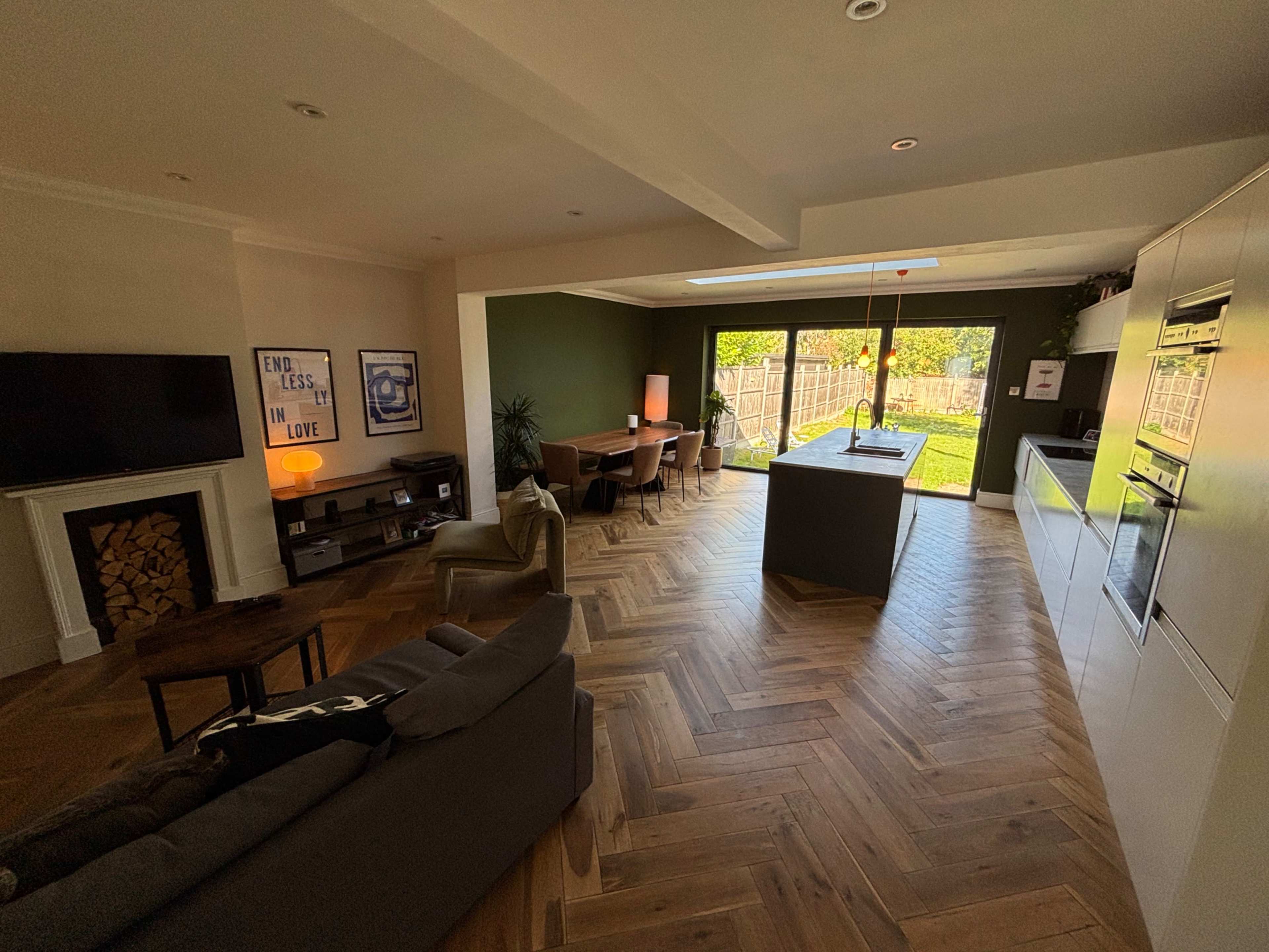 The image shows a modern, open-concept living area that includes a kitchen, dining space, and a cozy seating area with hardwood flooring.