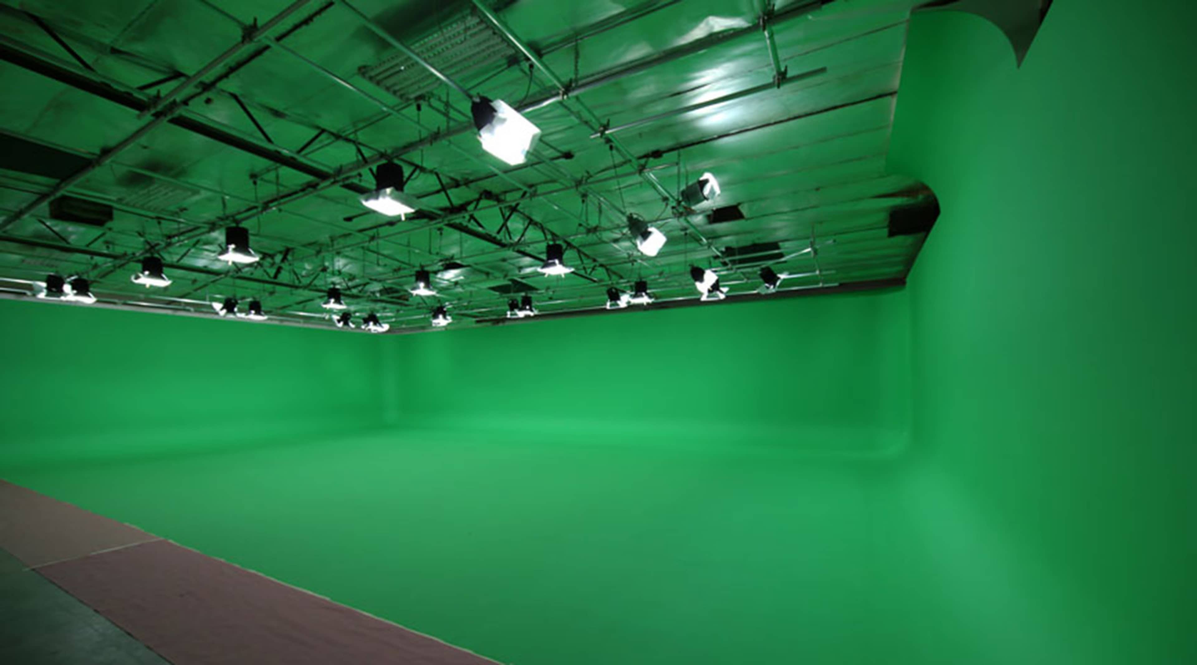 A large studio space with a smooth green backdrop and multiple overhead lights.