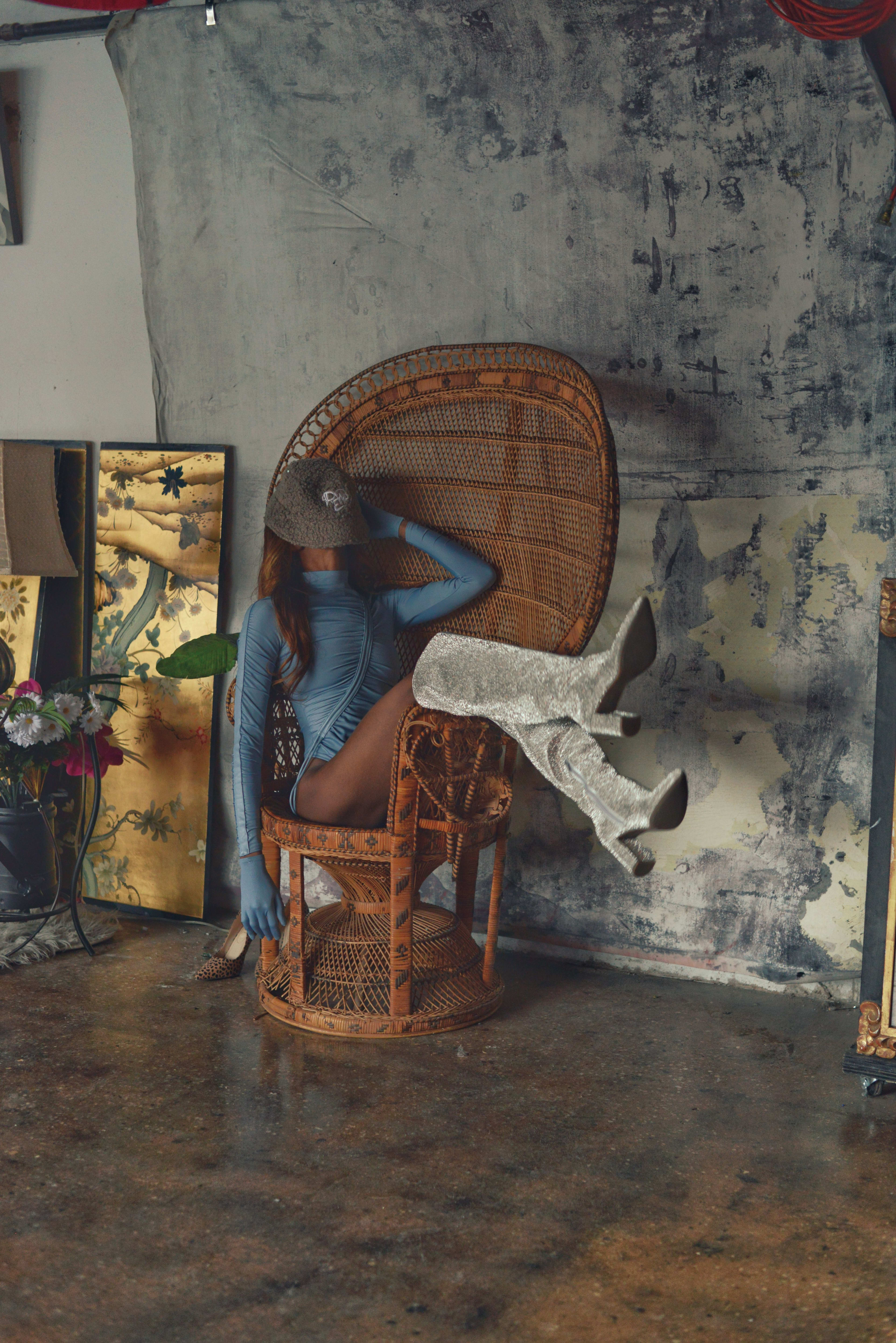 A woman with silver boots posing on a chair for a fashion photo shoot.