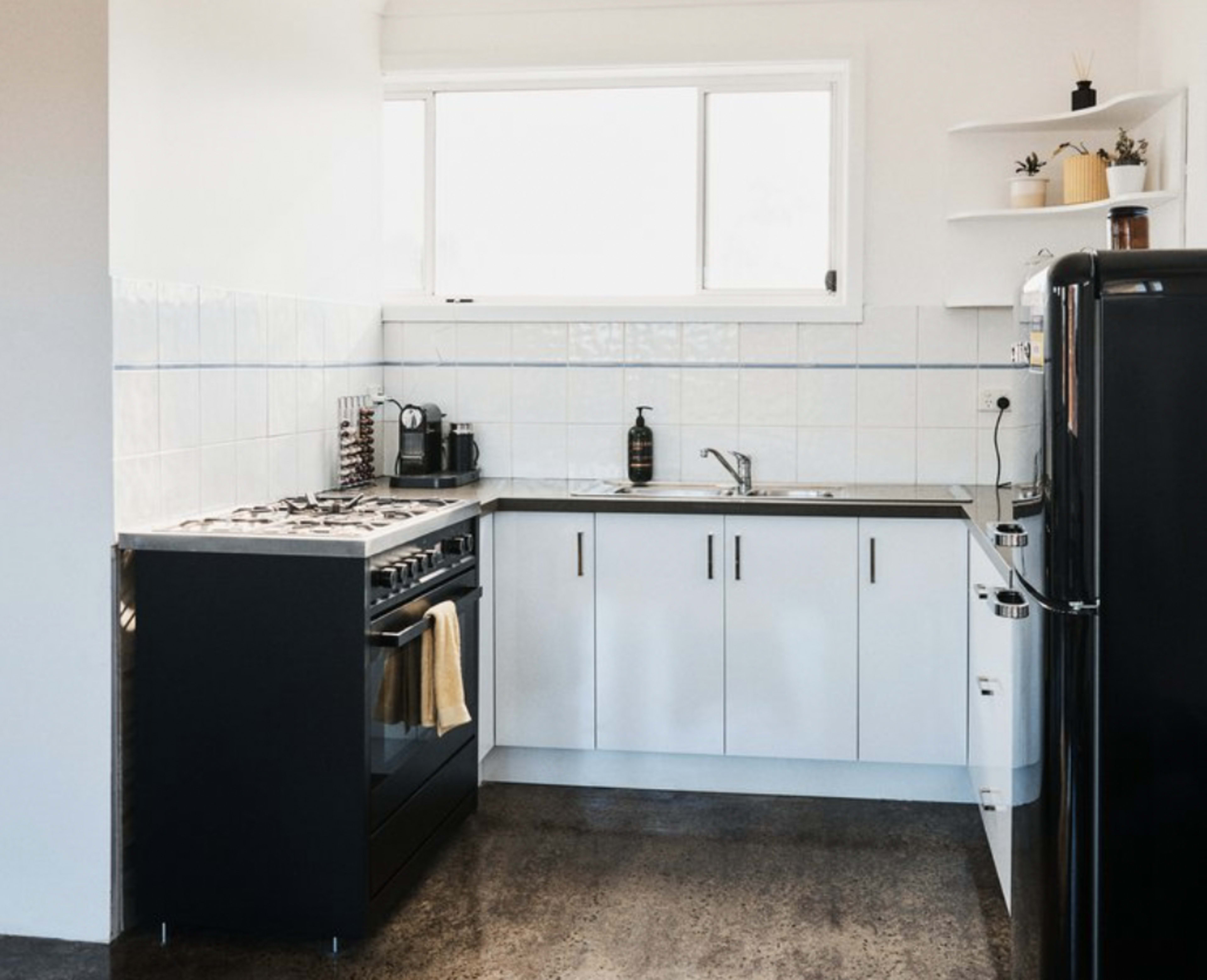 A modern kitchen with a gas stove, a stainless steel sink, and black and white cabinetry.