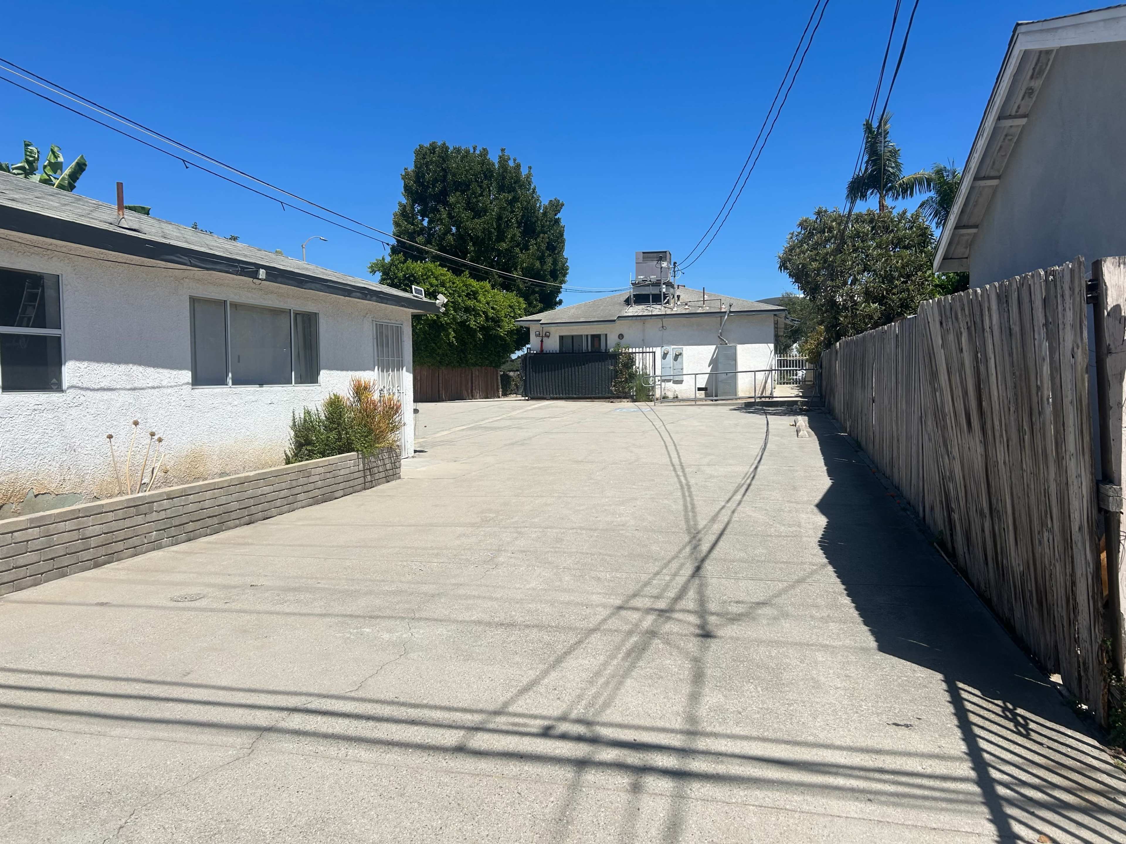 The image shows a paved alleyway lined with buildings on either side and a clear blue sky above.