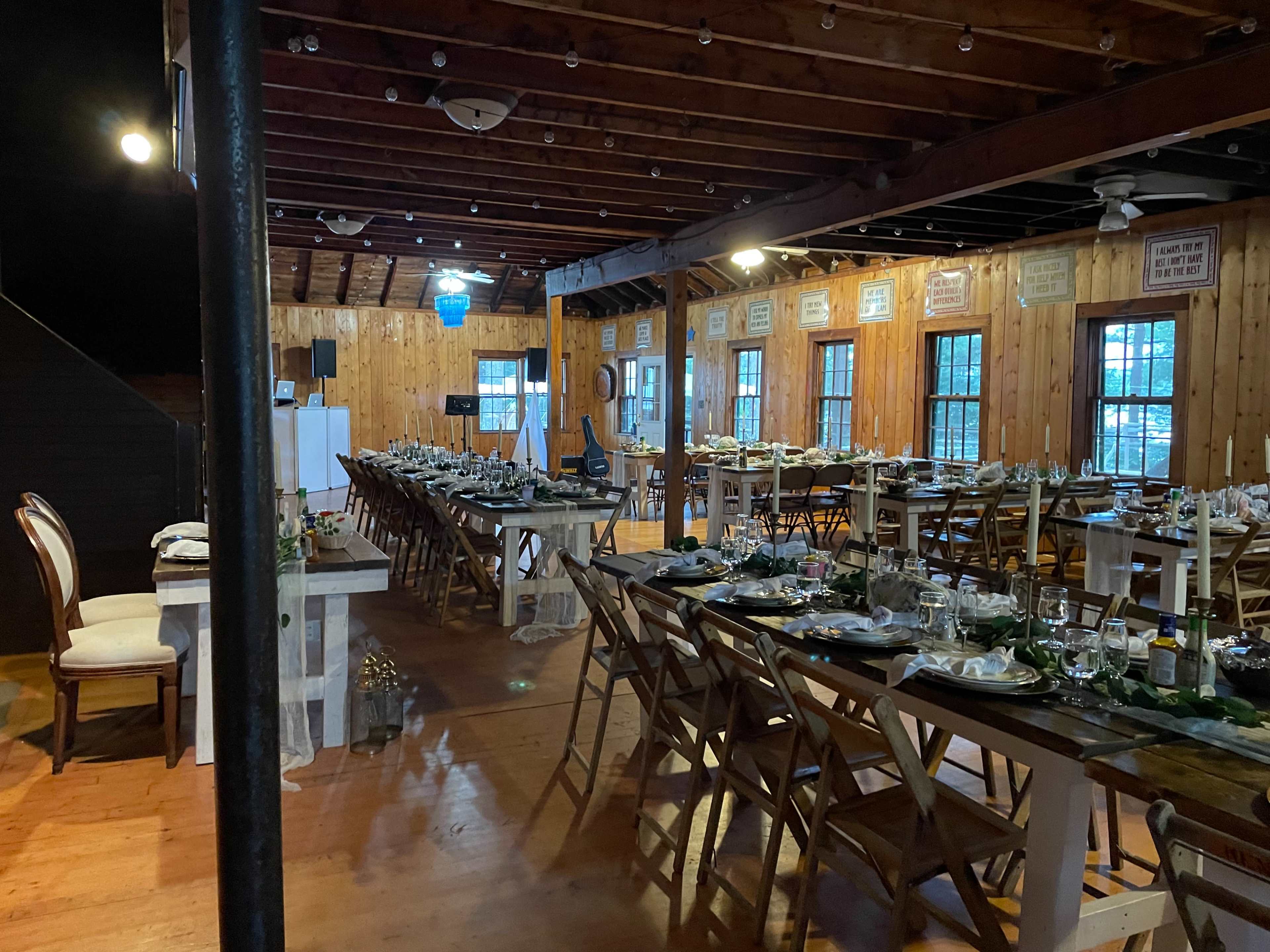 A large dining area decorated with tables set for a meal, featuring wooden beams and a rustic atmosphere.