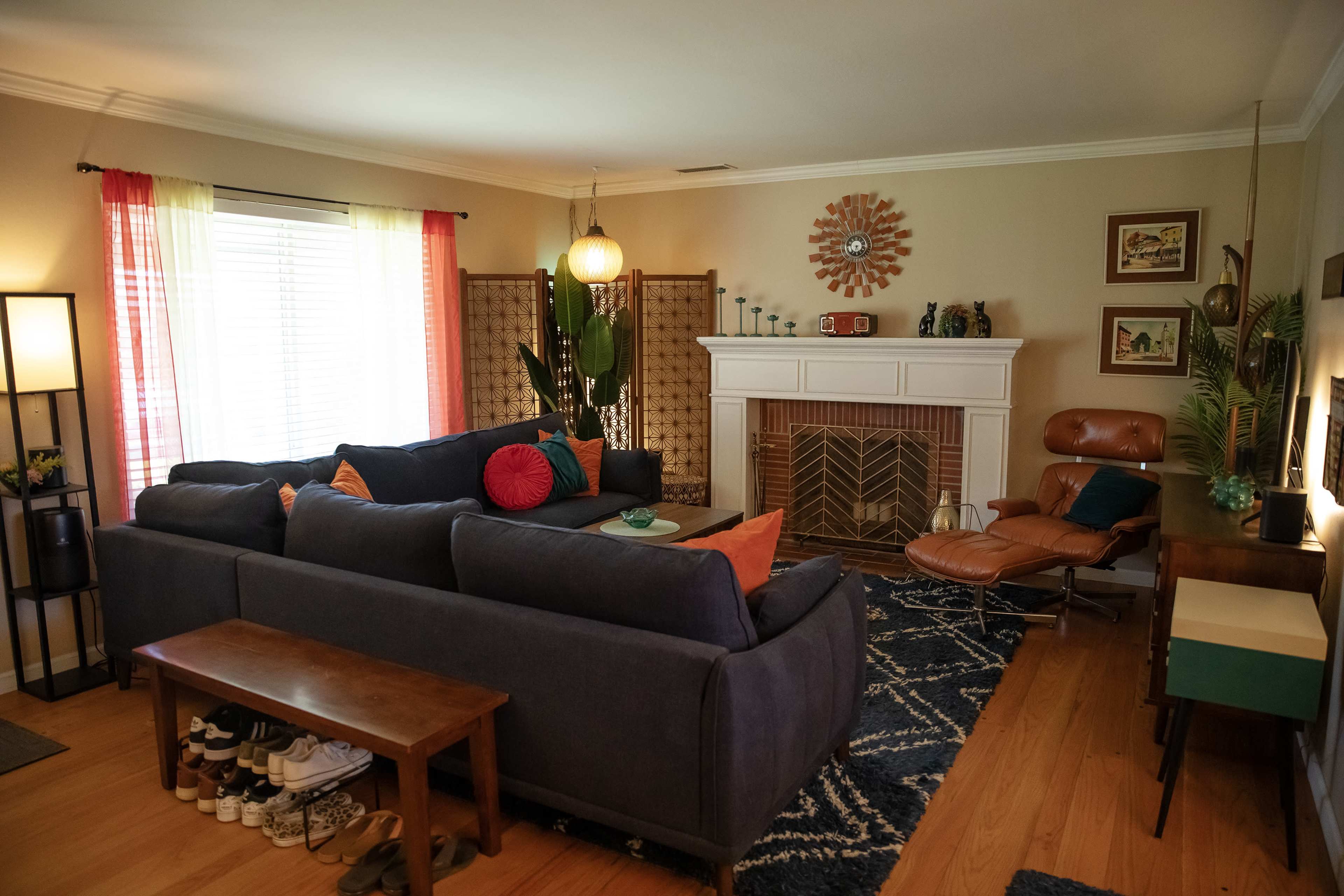 The living room features a sectional sofa, a wooden coffee table, a fireplace with a mantel, and various decorative elements, including plants and wall art.