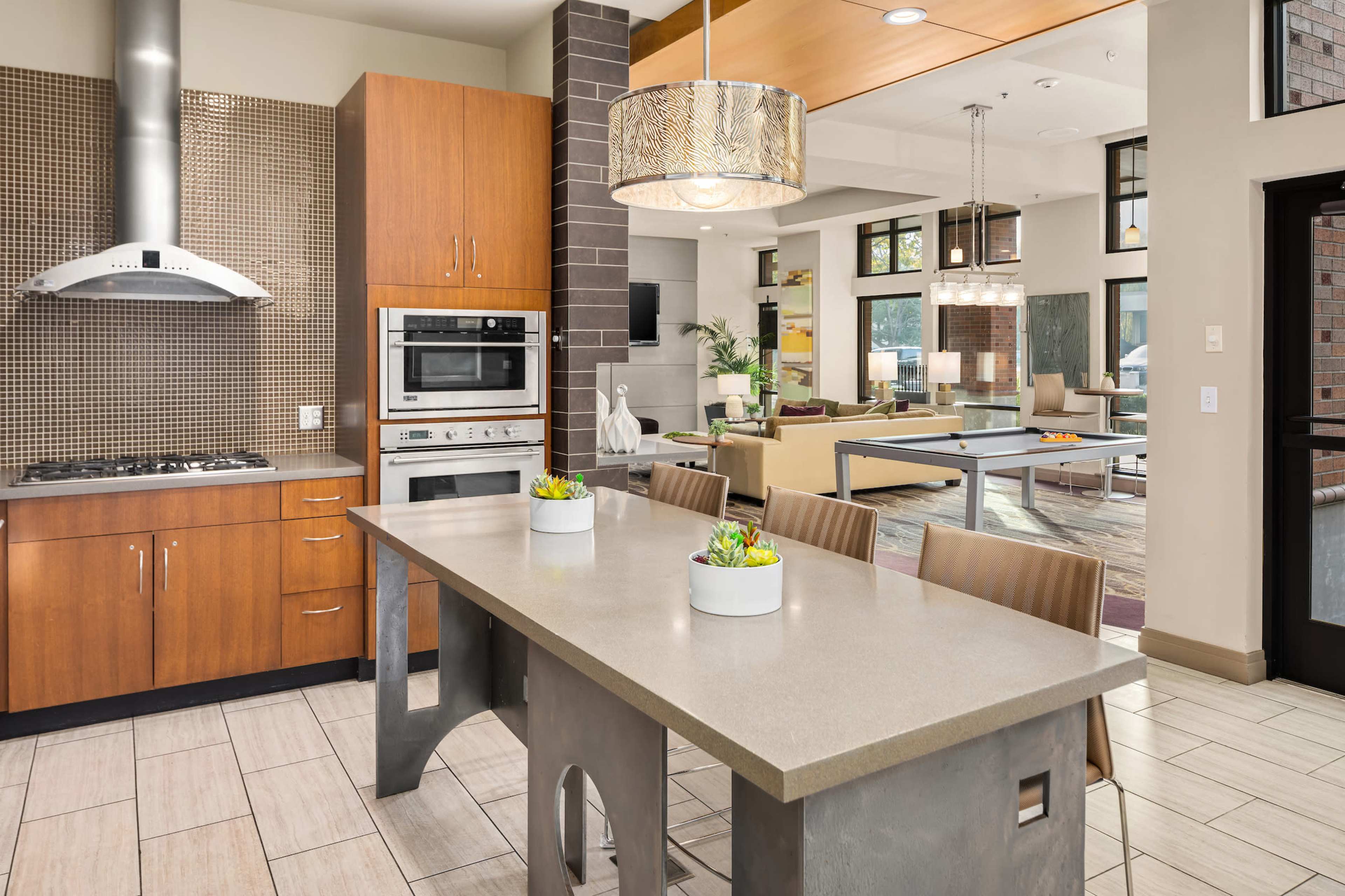 A modern kitchen with a central island, stainless steel appliances, and a seating area that opens into a spacious living room.
