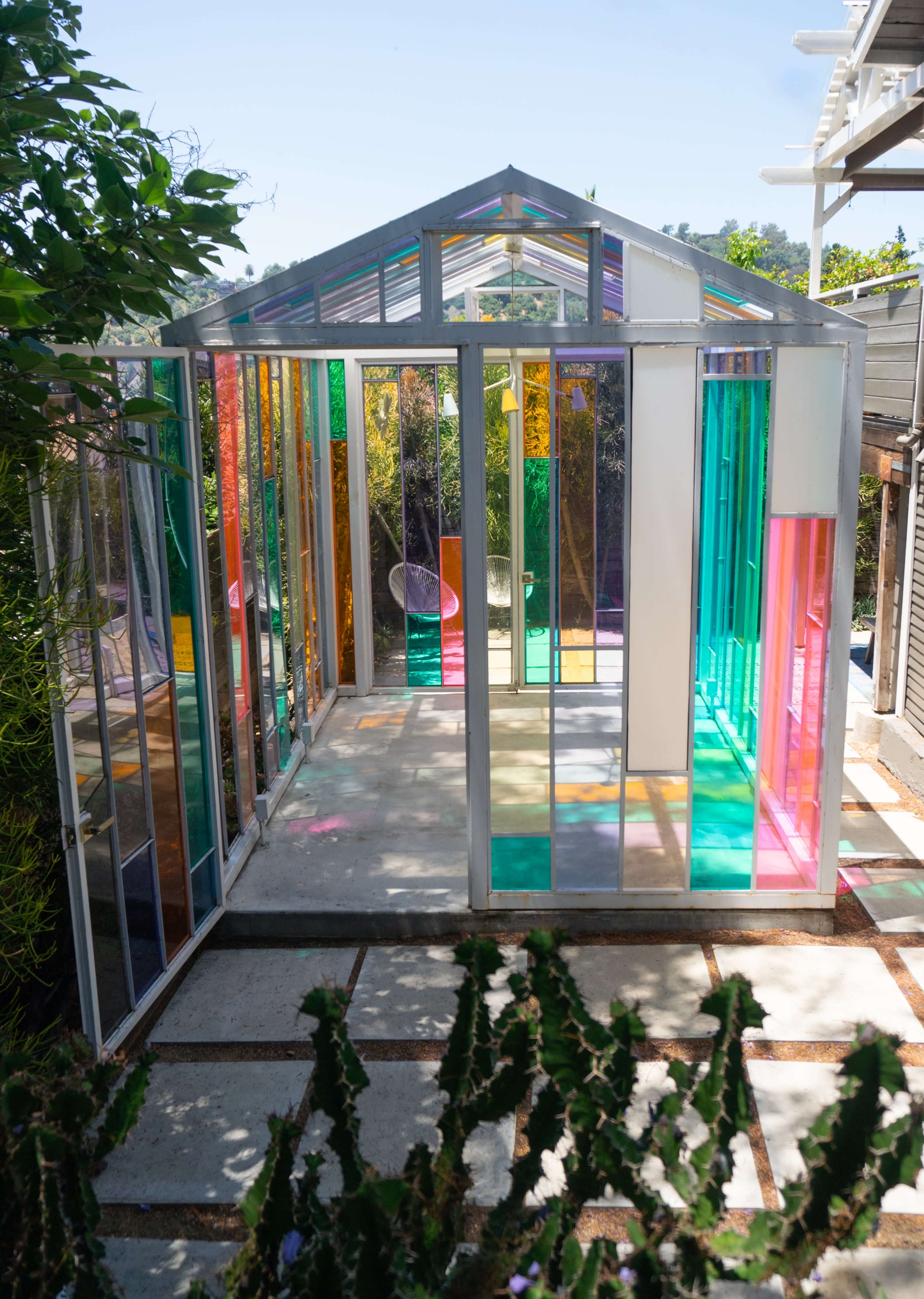 A greenhouse with colorful glass panels and an open structure that allows for sunlight to filter through.