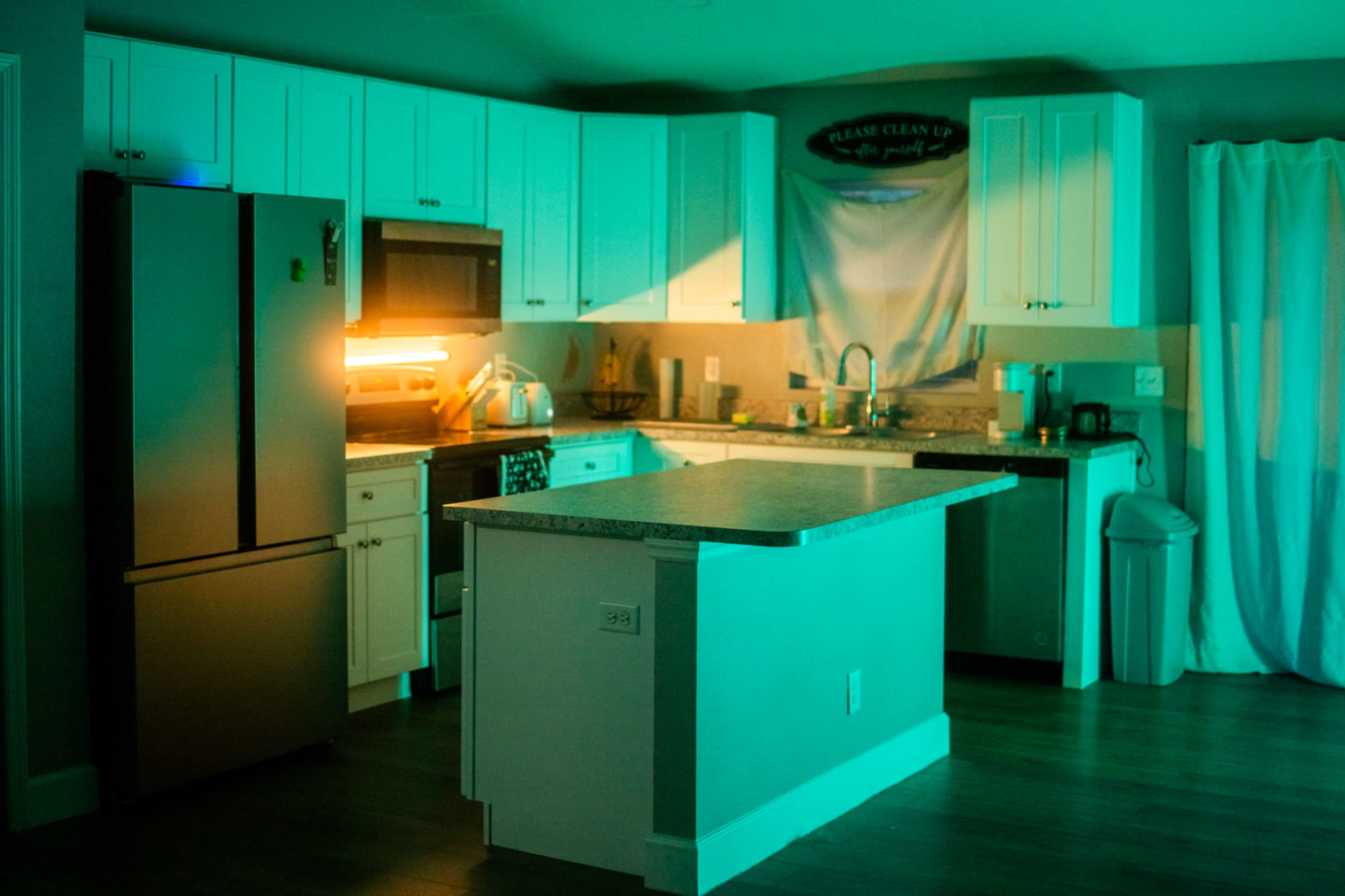 A modern kitchen features white cabinetry, a central island, and ambient lighting.