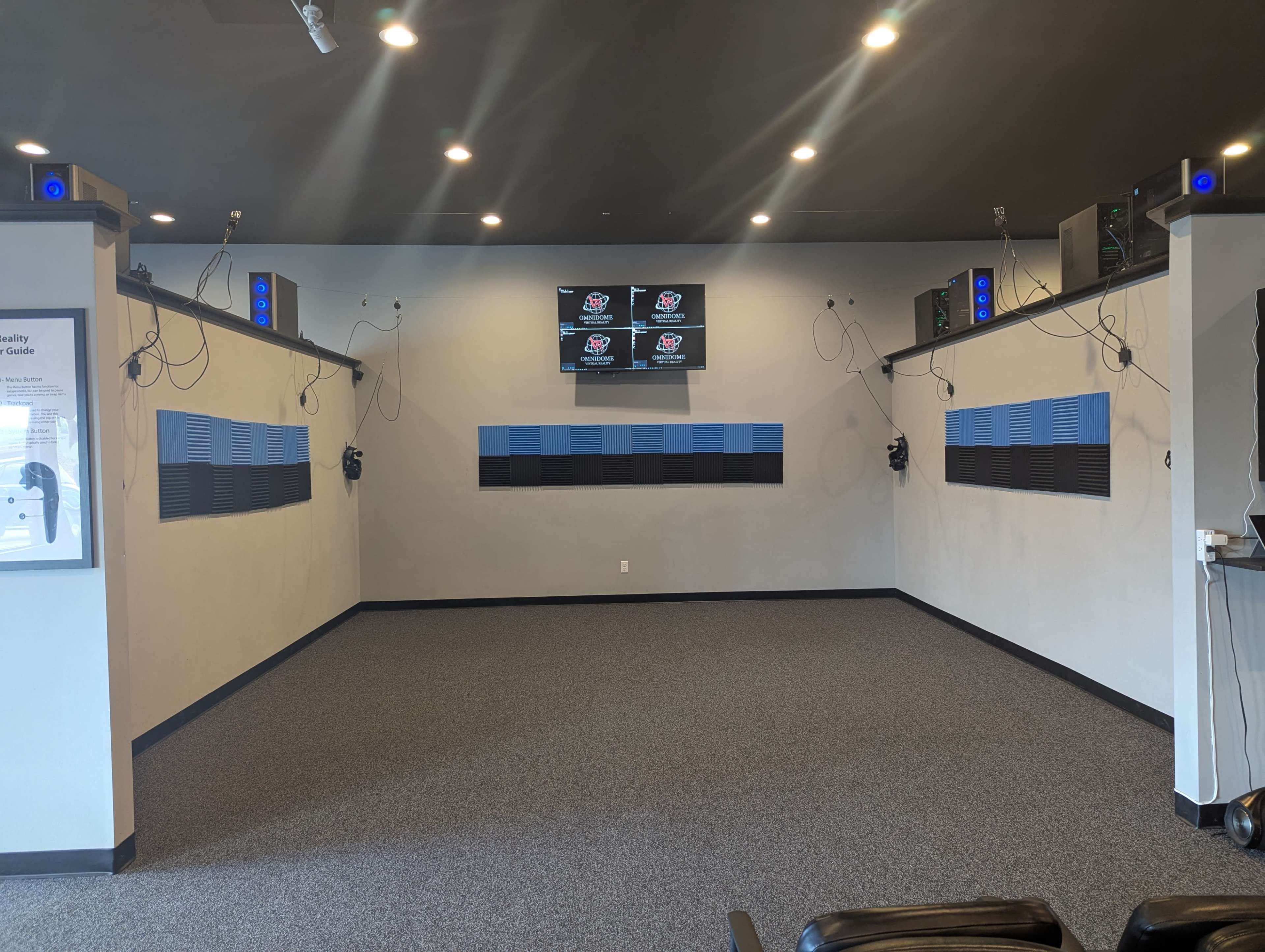The image shows a modern room designed for audio and visual presentations, featuring multiple screens, speakers, and soundproof panels on the walls.