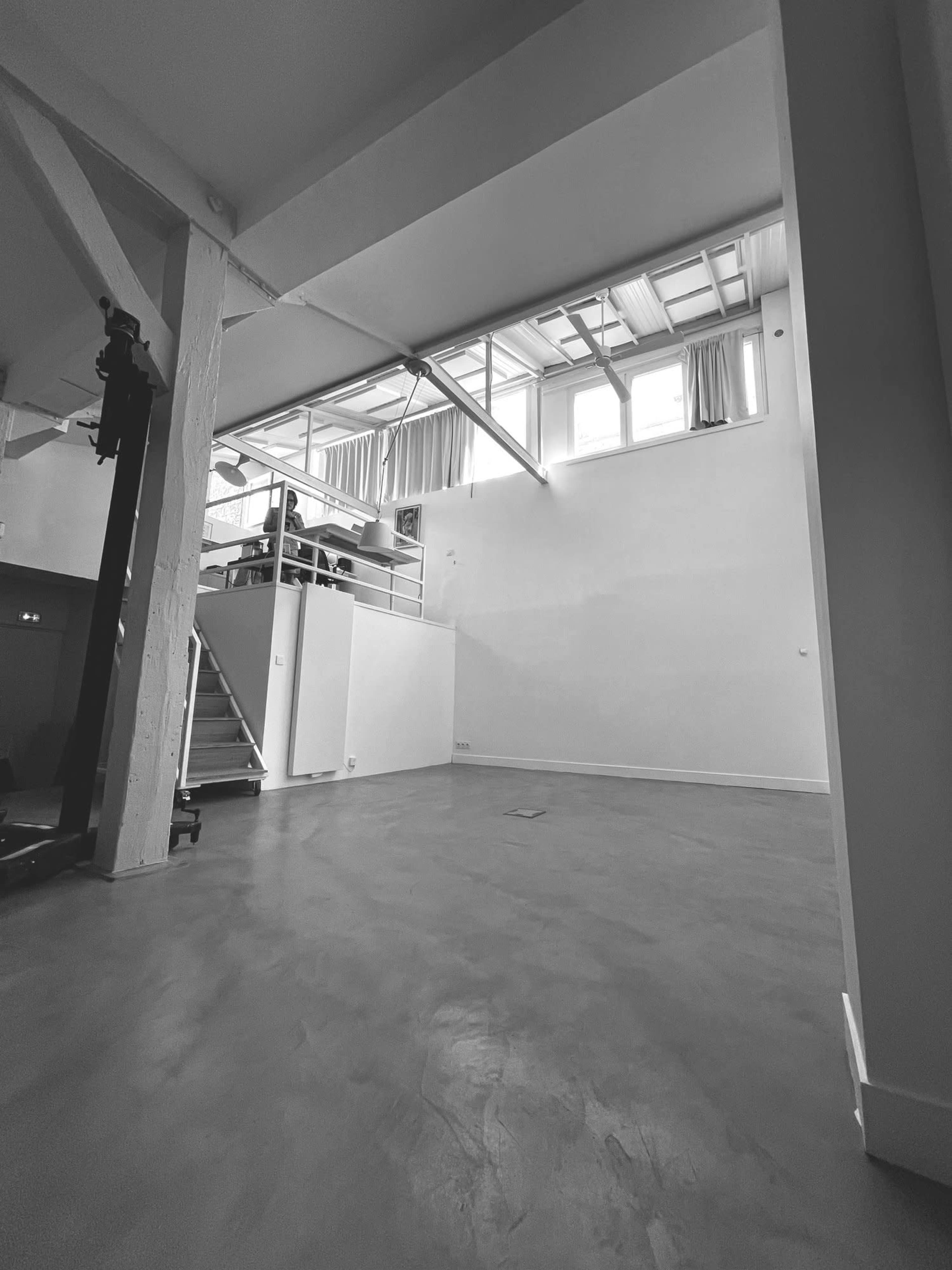An empty, spacious indoor area with high ceilings and large windows providing natural light.
