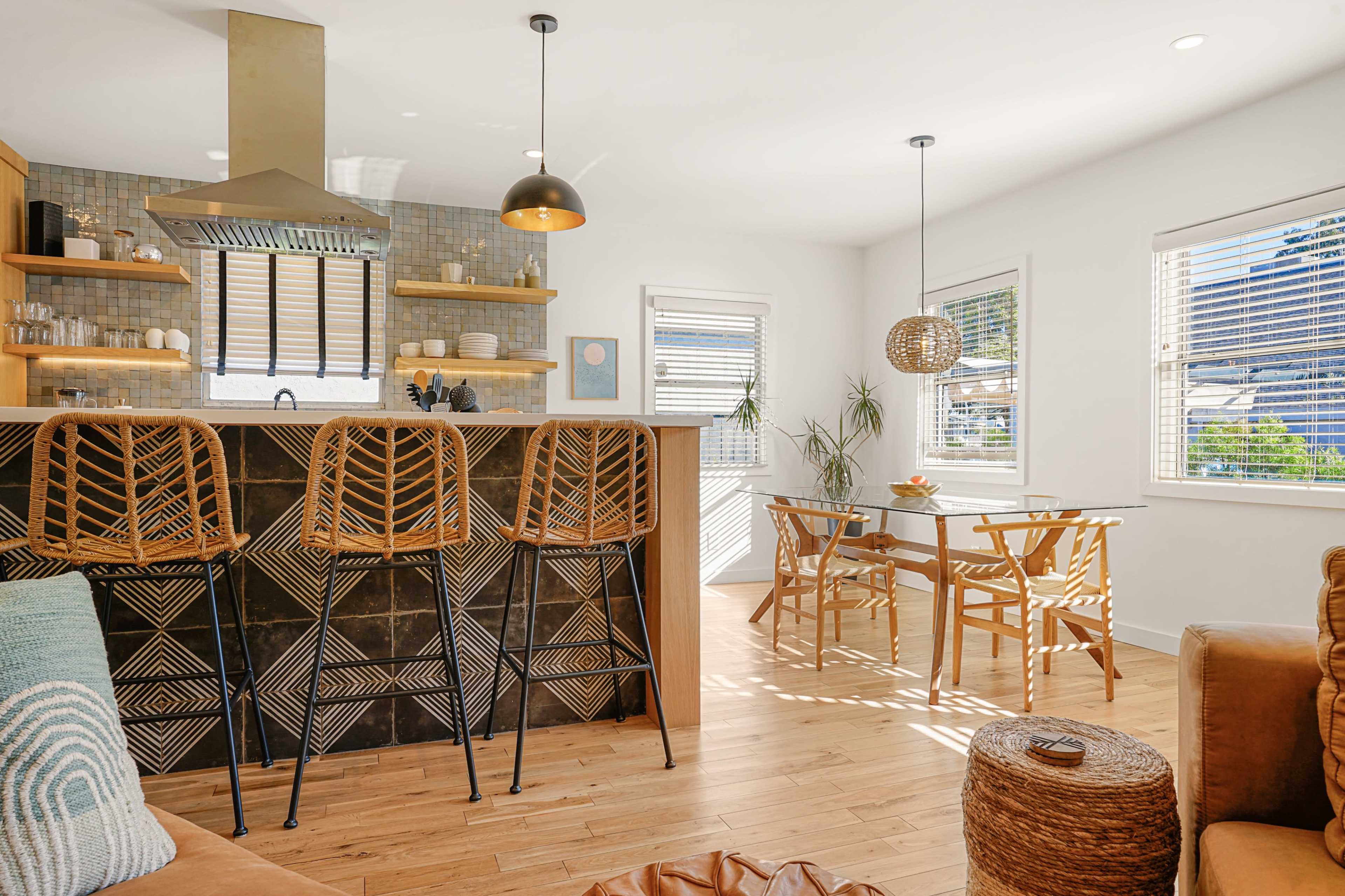 A bright, modern kitchen and dining area with wooden floors, a large kitchen island with bar stools, and a dining table set for a meal.