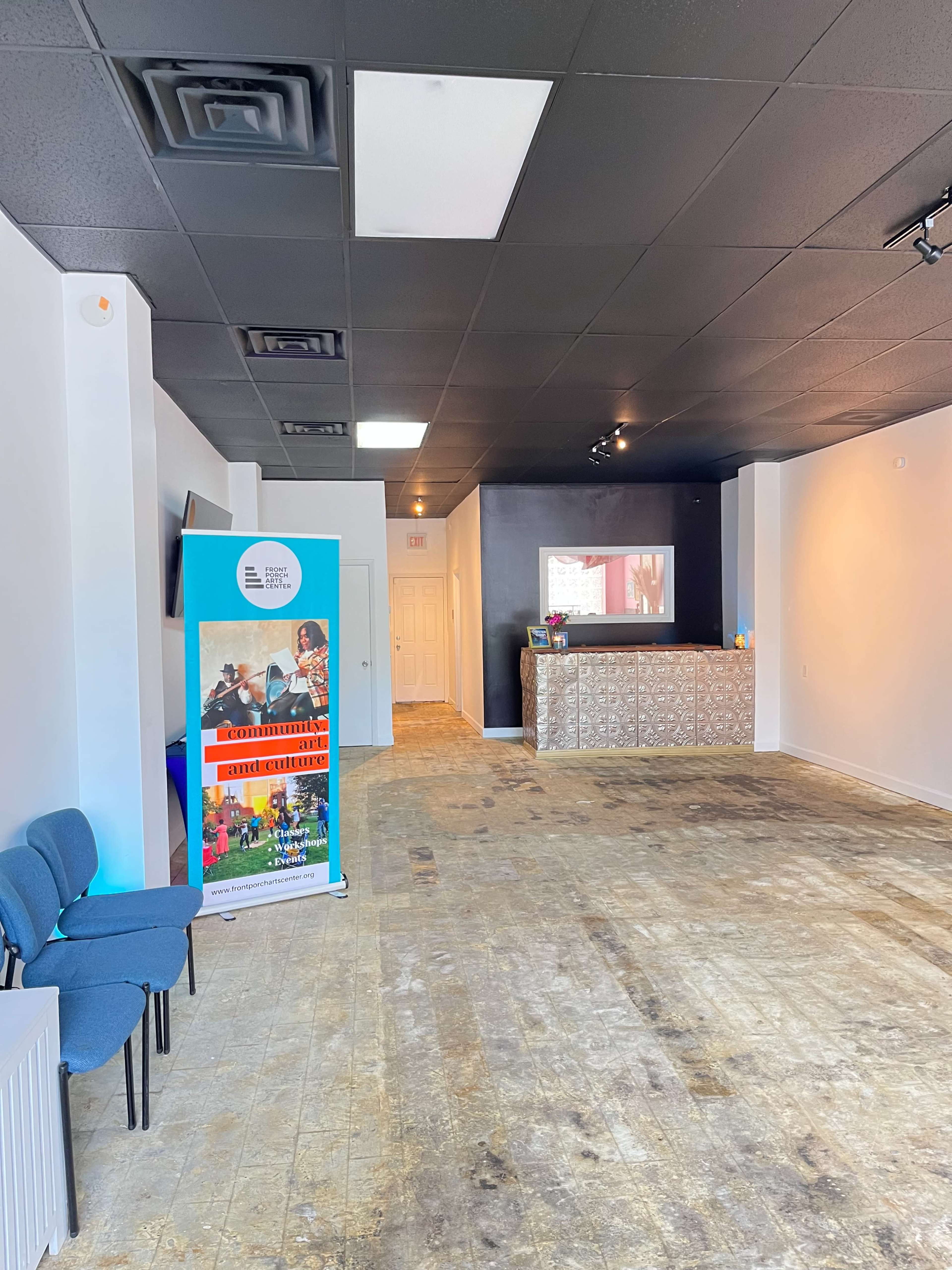 An empty indoor space with a reception area featuring a blue banner and a low counter with decorative tiles.