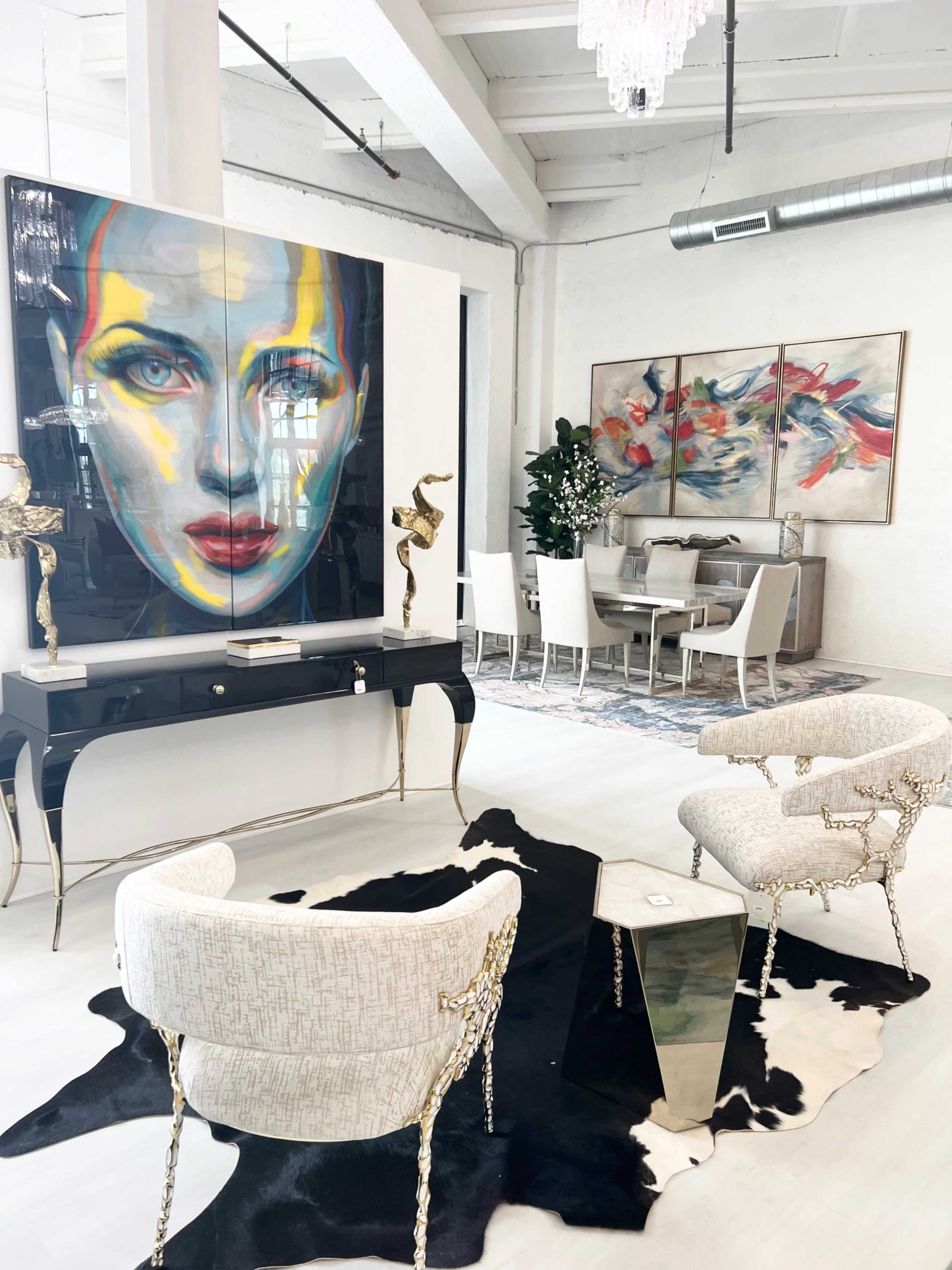 The image features a modern interior with a bold portrait painting, elegant furniture, and a dining area, all set against a bright, open space.